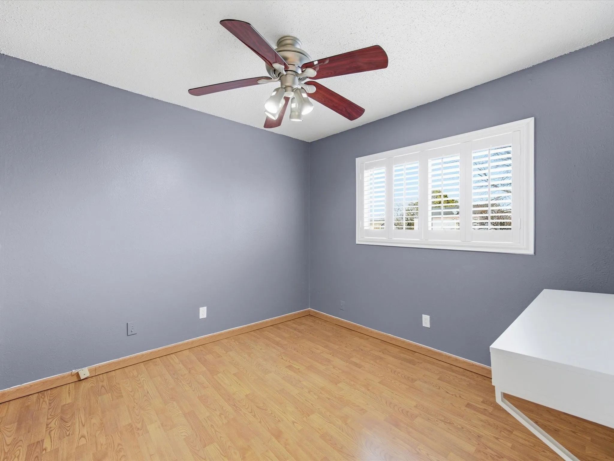 Bedroom featuring light wood-style floors, a ceiling fan, and a textured ceiling