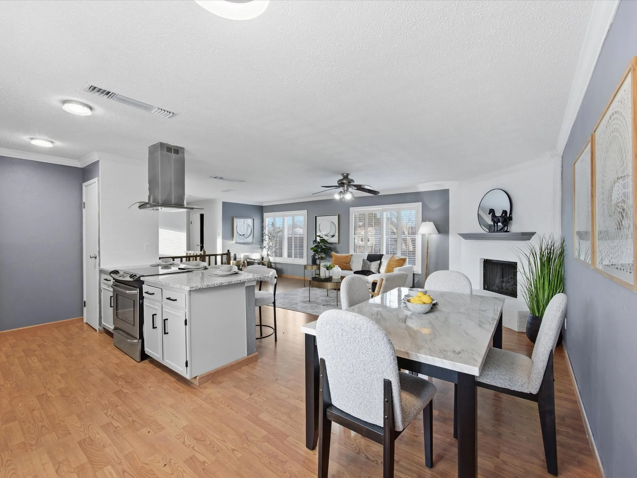 Kitchen with island range hood, open floor plan, stainless steel range with electric stovetop, and light stone counters