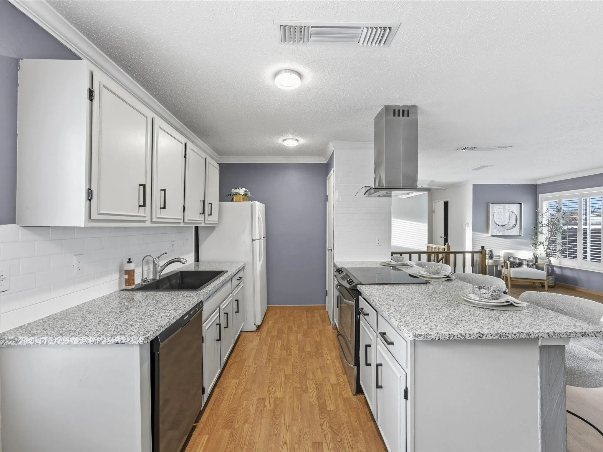 Kitchen with island exhaust hood, a peninsula, light stone countertops, decorative backsplash, and light wood-style flooring