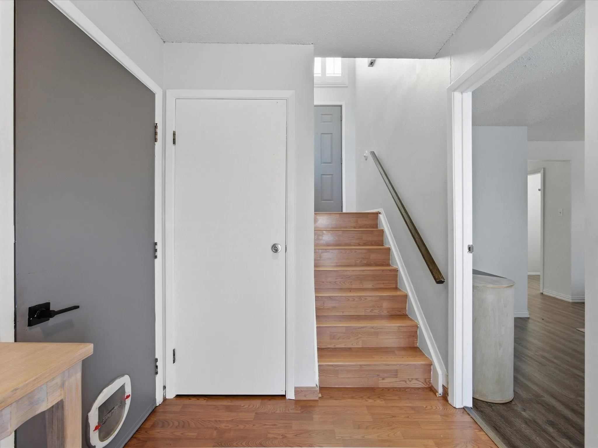 Stairway with wood finished floors and a textured ceiling