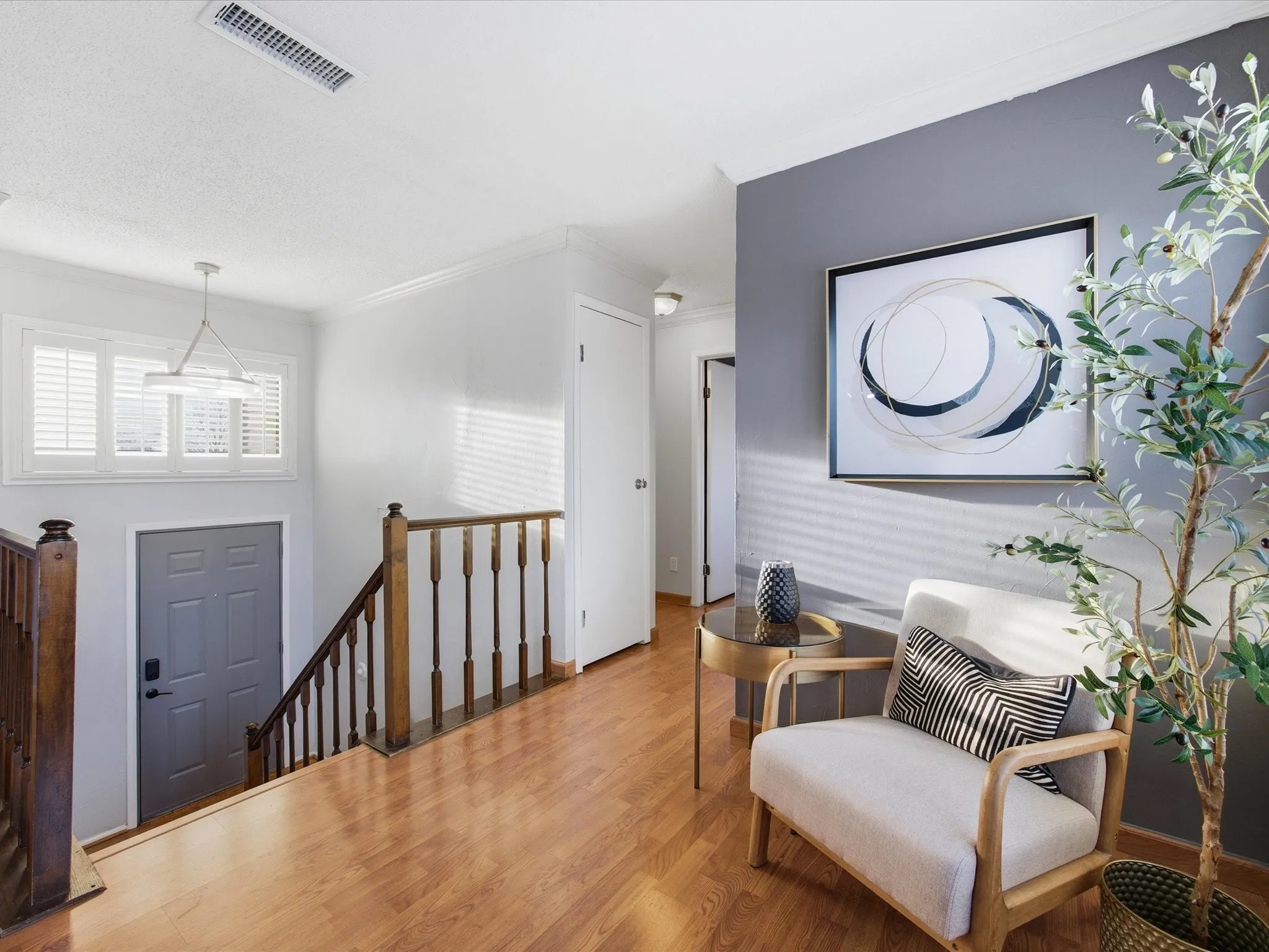 Sitting room with an upstairs landing, wood finished floors, and crown molding