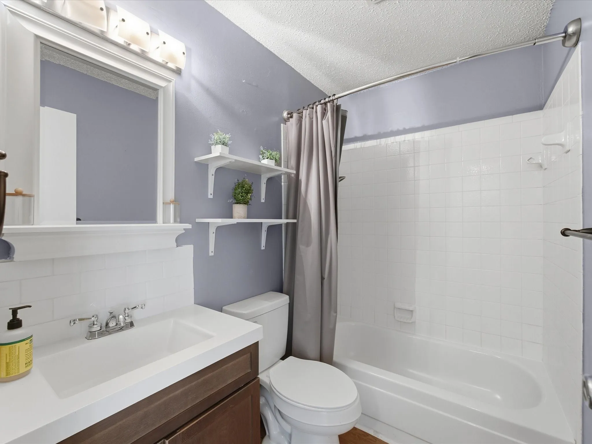 Full bathroom with backsplash, shower / tub combo with curtain, vanity, and a textured ceiling