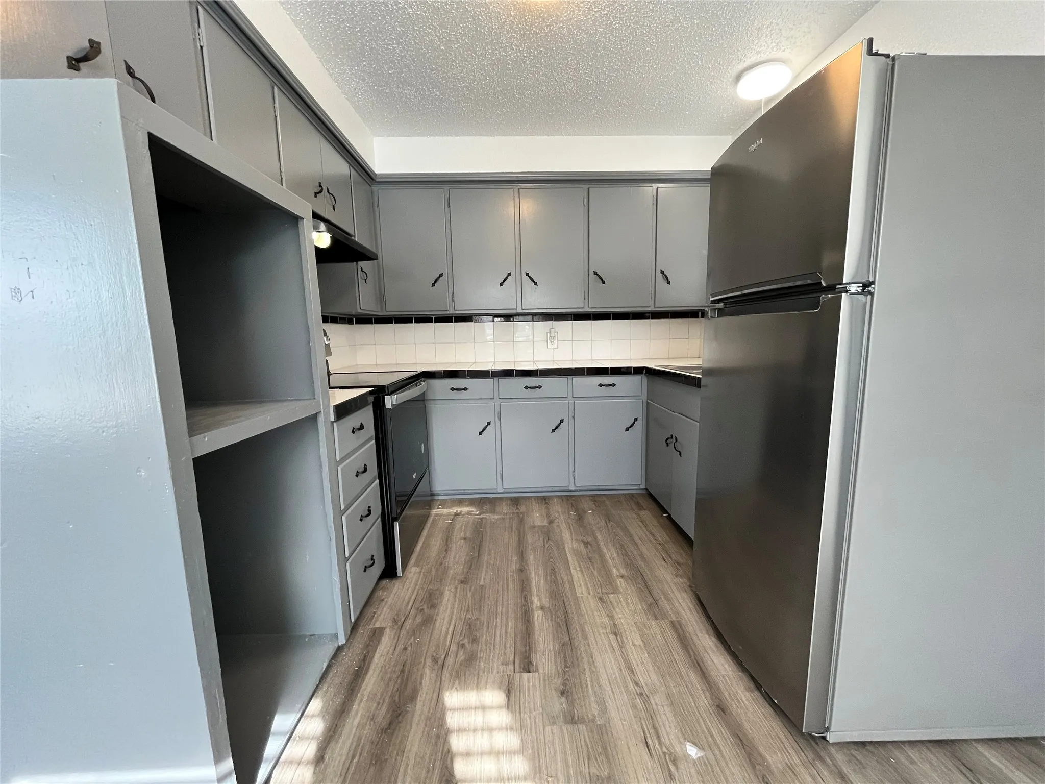 This is another view of the kitchen, displaying the giant storage shelf. Notice that the appliances are all brand new.