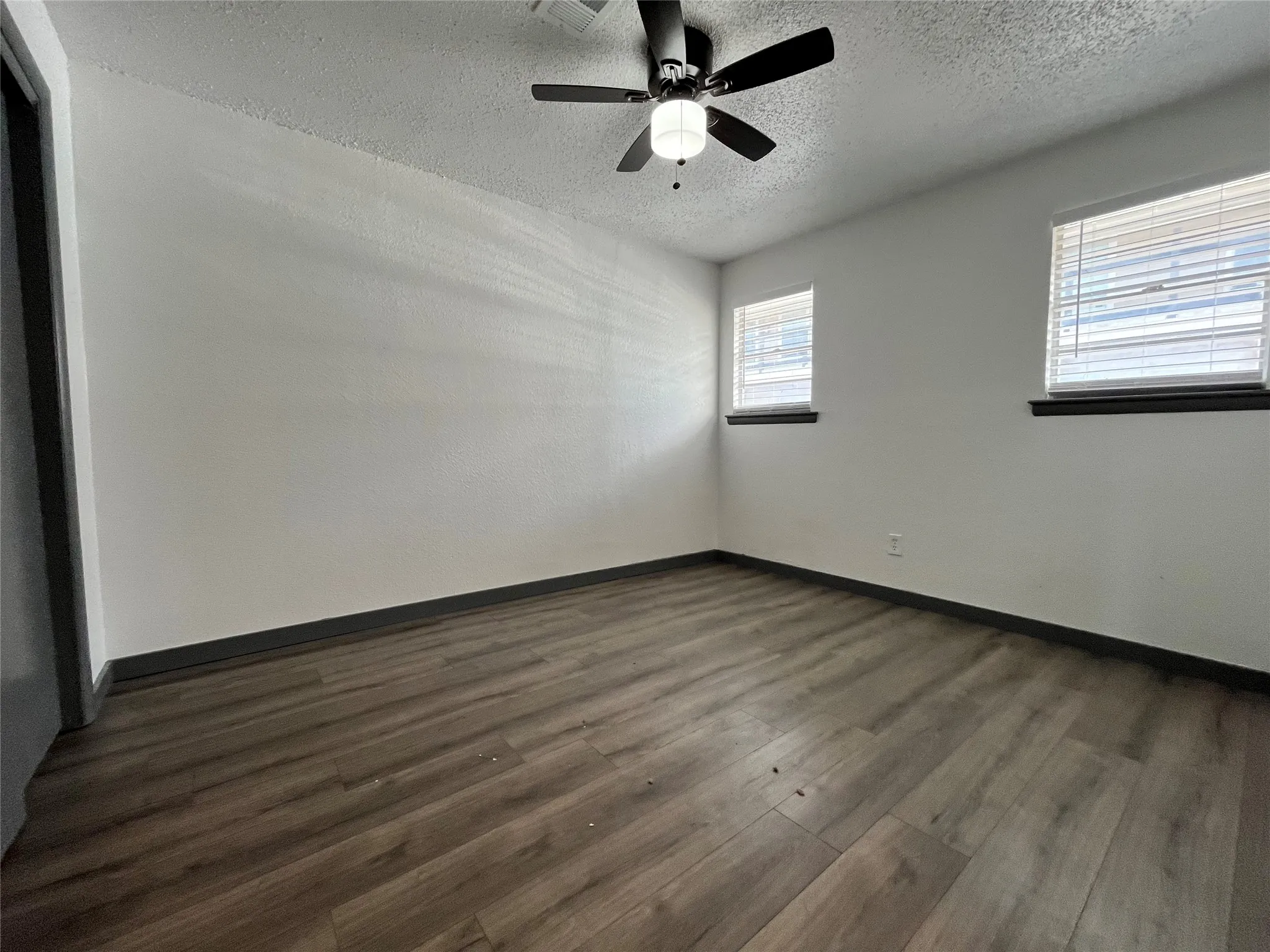 This is a view of the second bedroom, equipped with a brand new lighted ceiling fan. Notice the natural lighting coming in from the two windows and the new flooring.