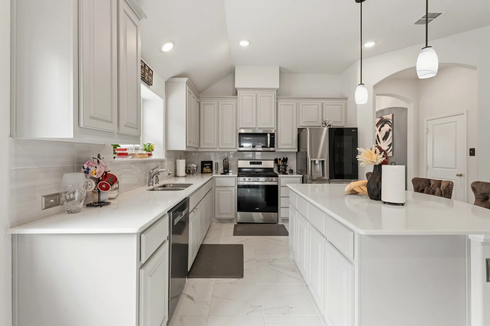 Kitchen featuring stainless steel appliances, a center island, tasteful backsplash, light marble finish floors, and a kitchen breakfast bar