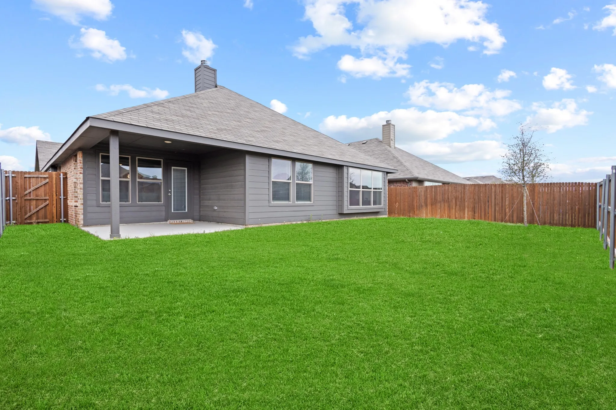 Rear view of property with a fenced backyard, a gate, a patio area, and a chimney