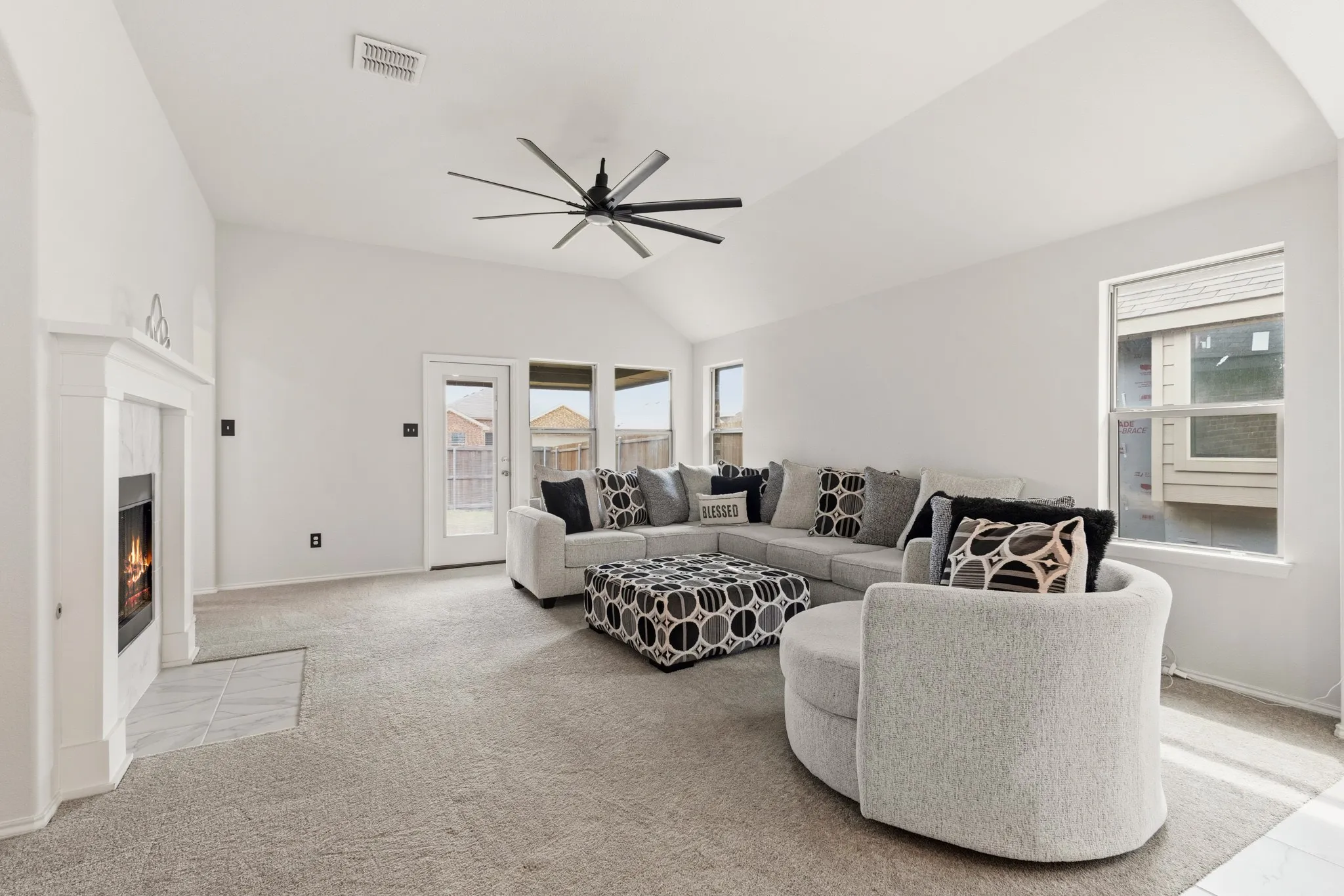 Living room featuring light colored carpet, lofted ceiling, a fireplace, and ceiling fan