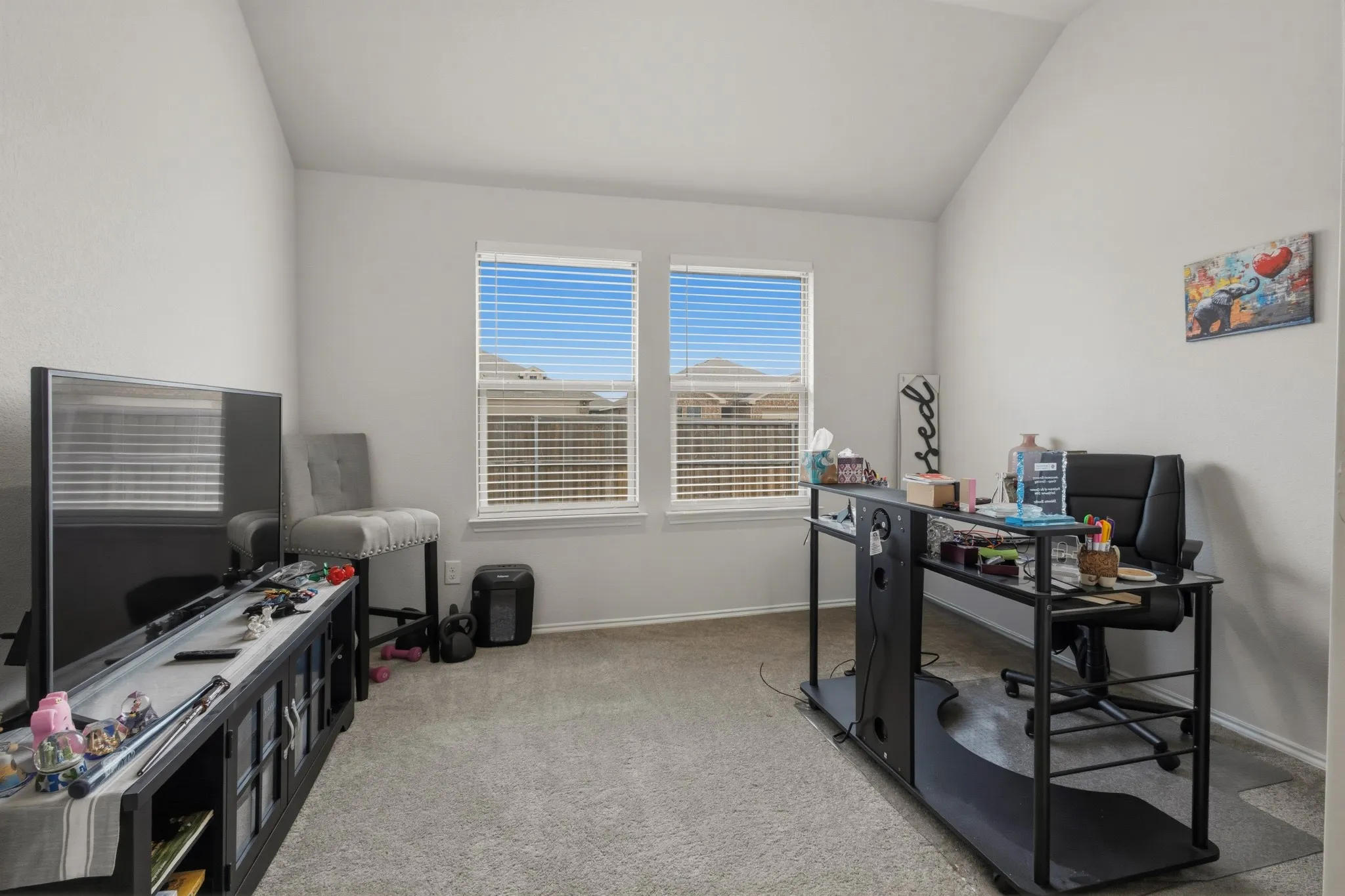 Office space with vaulted ceiling and light colored carpet