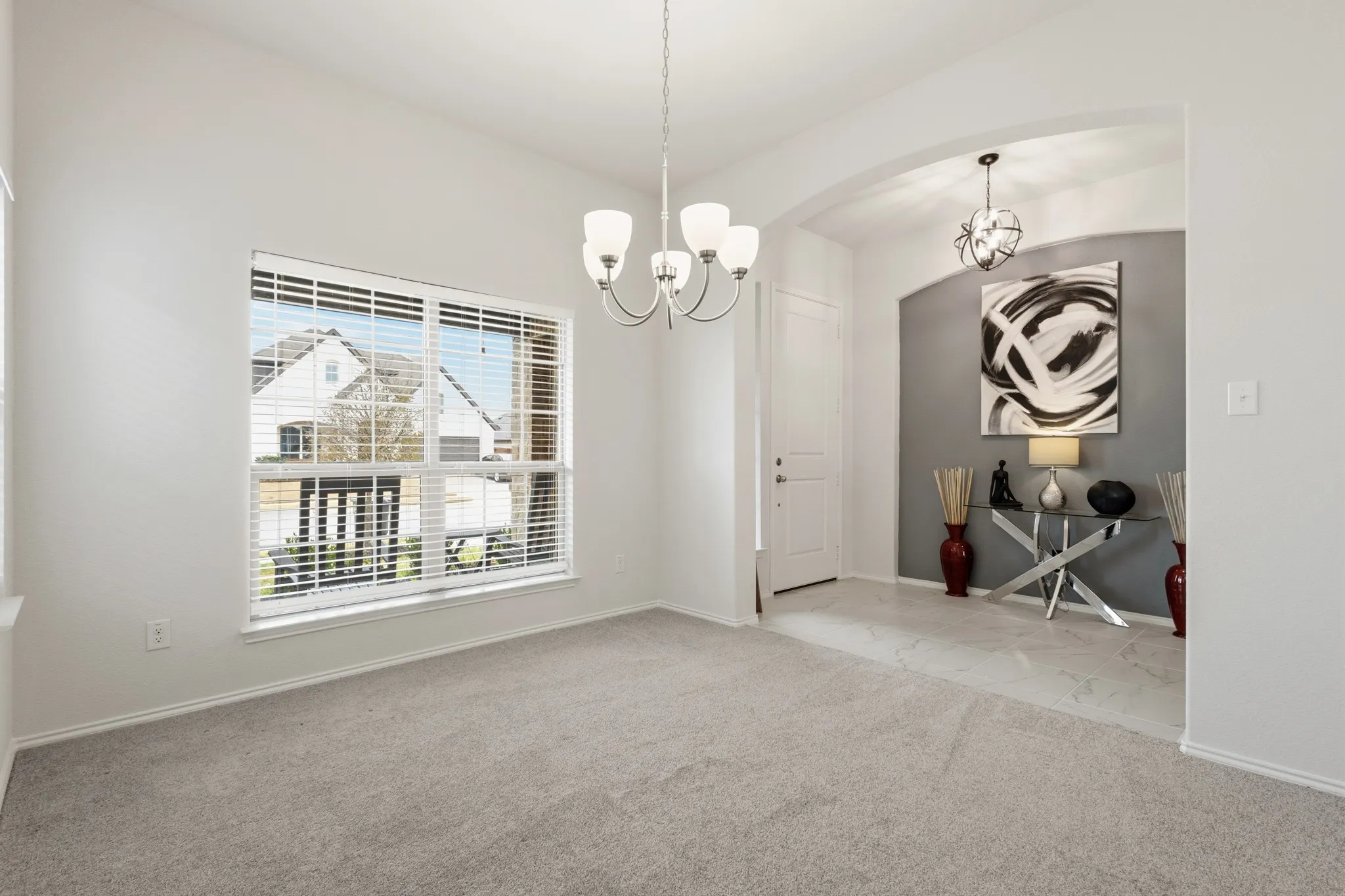 Formal dining room and front entry way featuring a chandelier, light carpet, and arched walkways