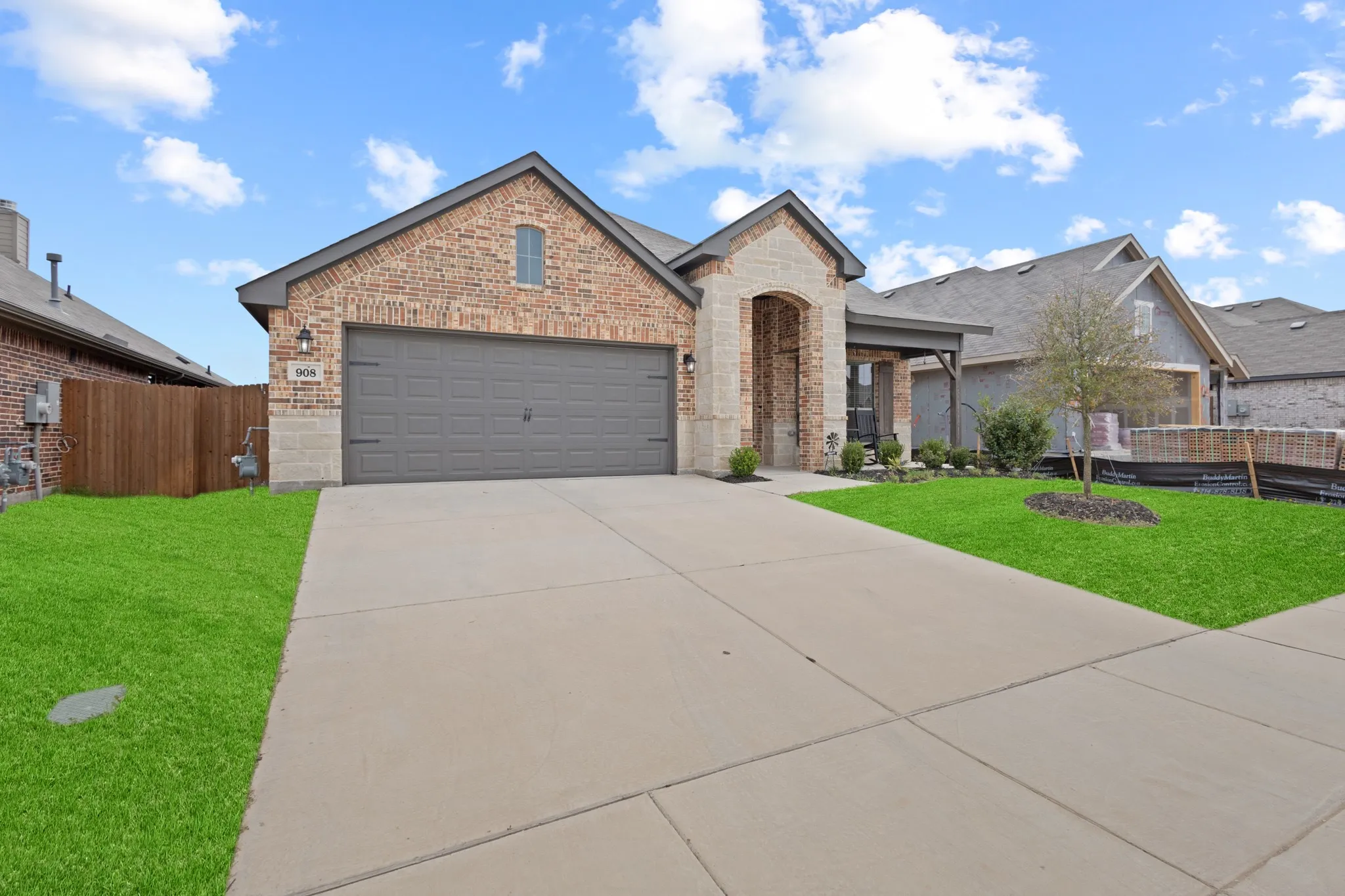French country style house with brick siding, an attached garage, concrete driveway, stone siding, and covered porch