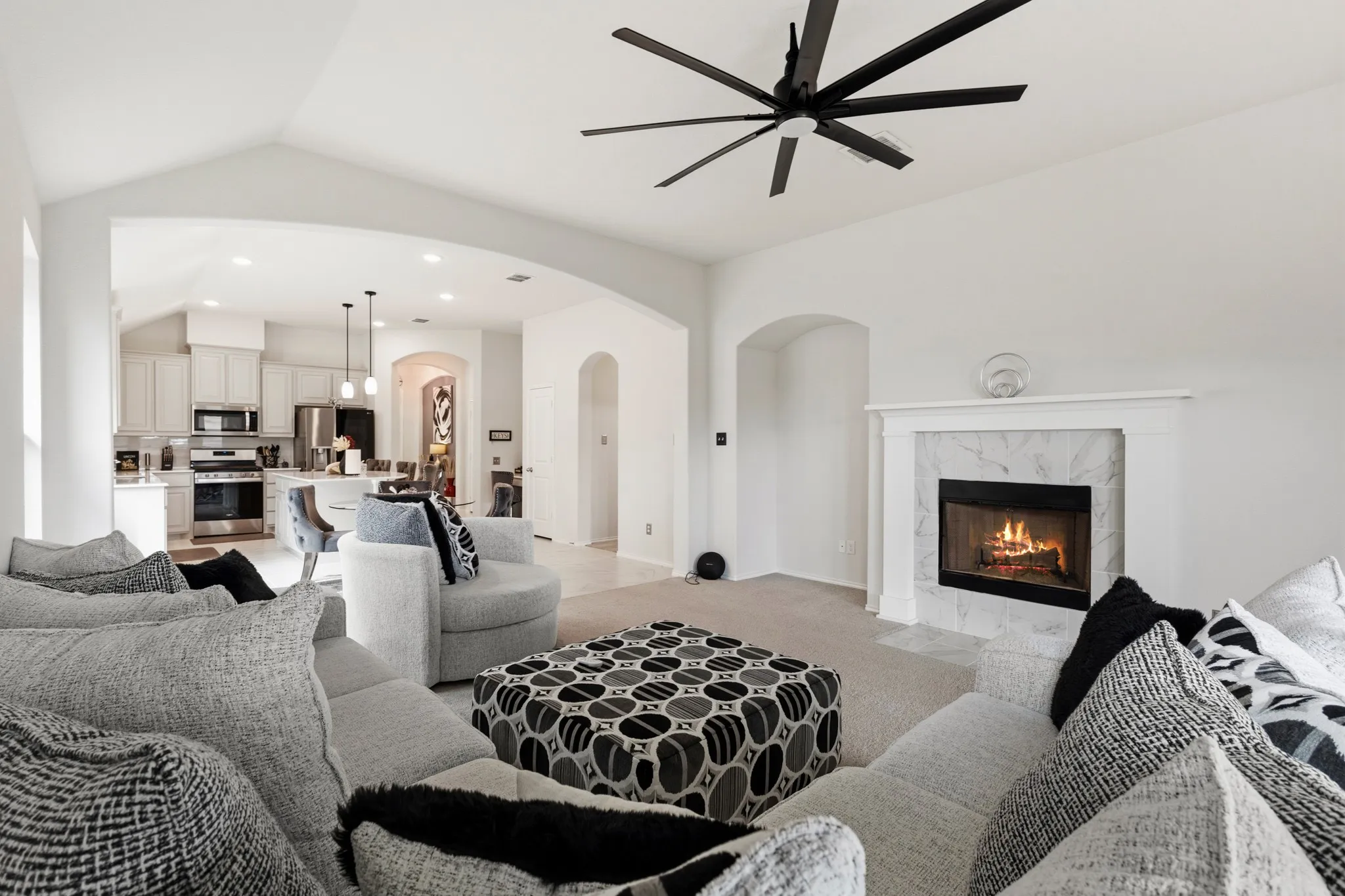 Carpeted living room with a ceiling fan, a premium fireplace, arched walkways, recessed lighting, and lofted ceiling