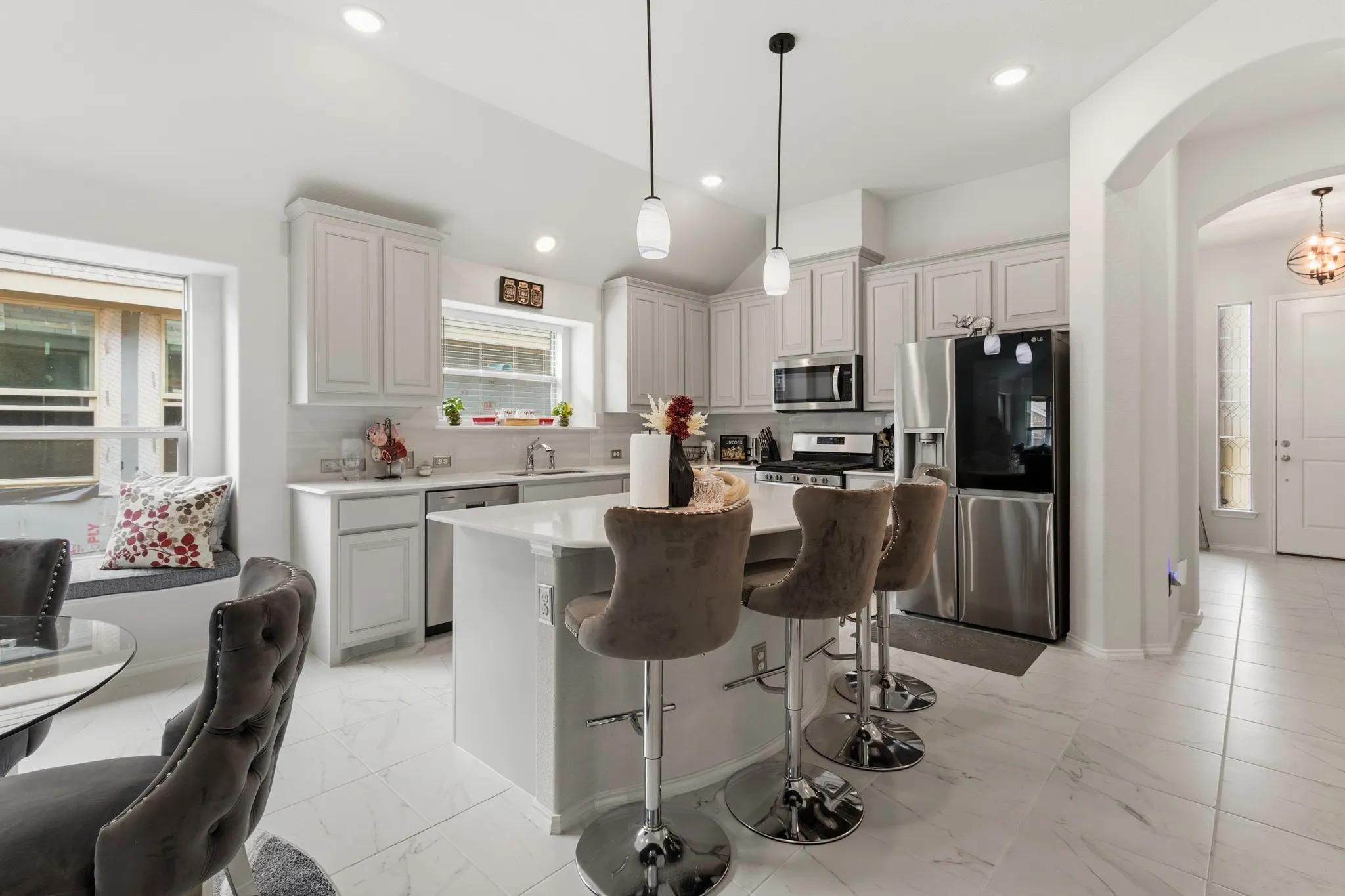 Kitchen featuring stainless steel appliances, arched walkways, a kitchen island, a breakfast bar area, and decorative light fixtures