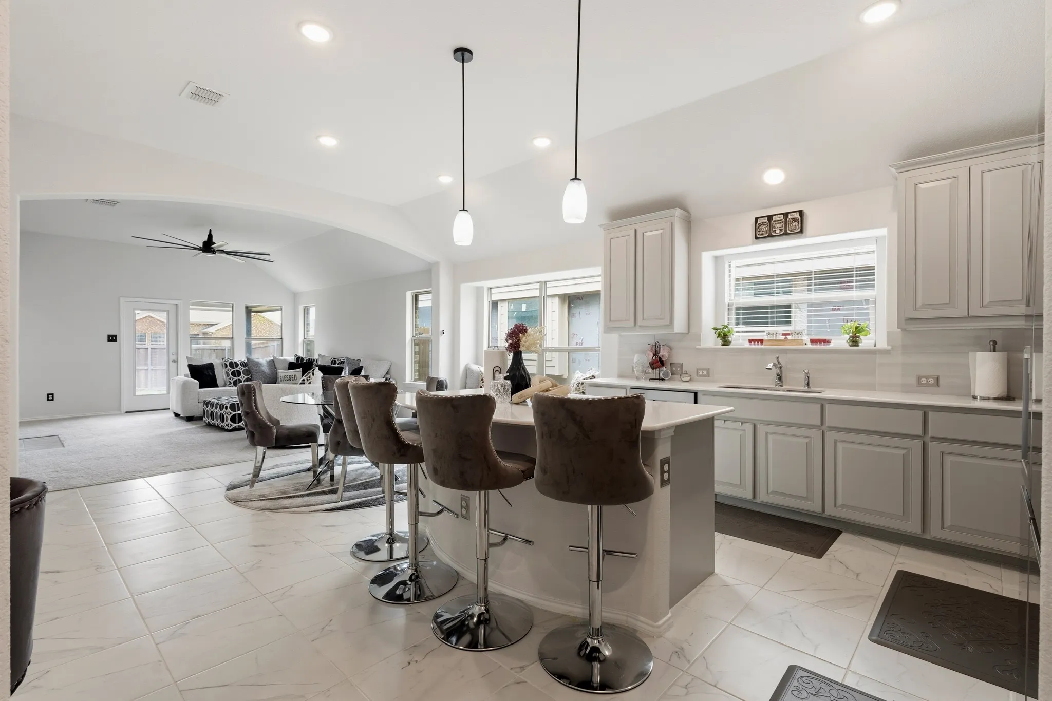 Kitchen featuring tasteful backsplash, lofted ceiling, open floor plan, a breakfast bar, and pendant lighting