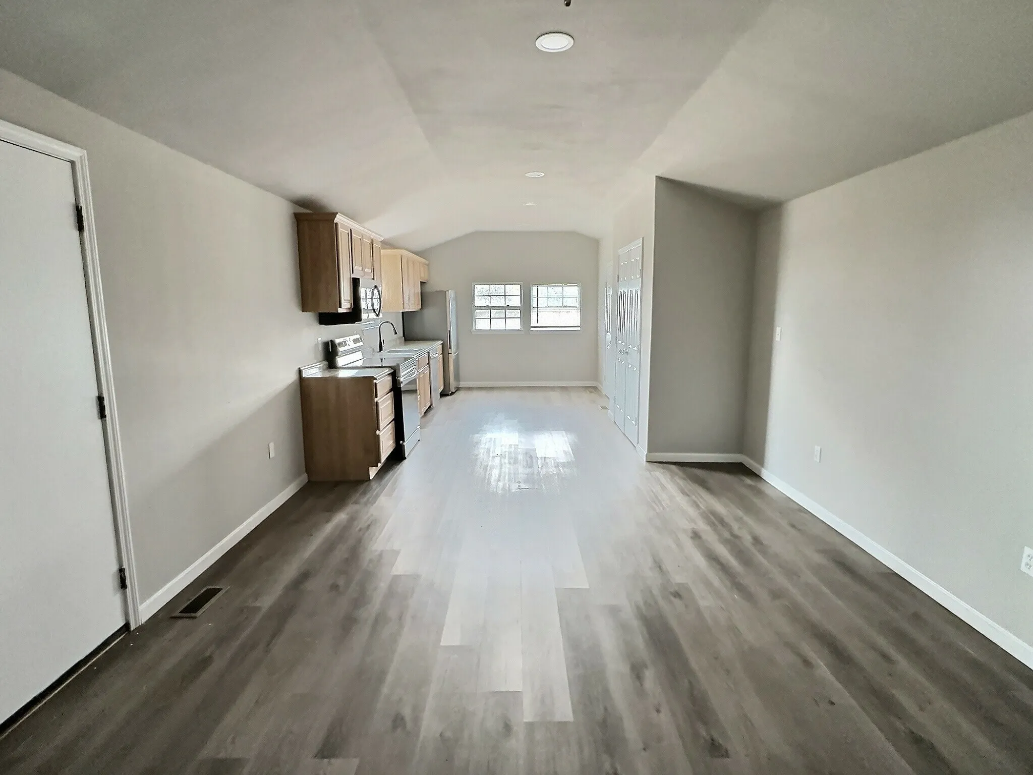 Unfurnished living room featuring vaulted ceiling and light wood-type flooring