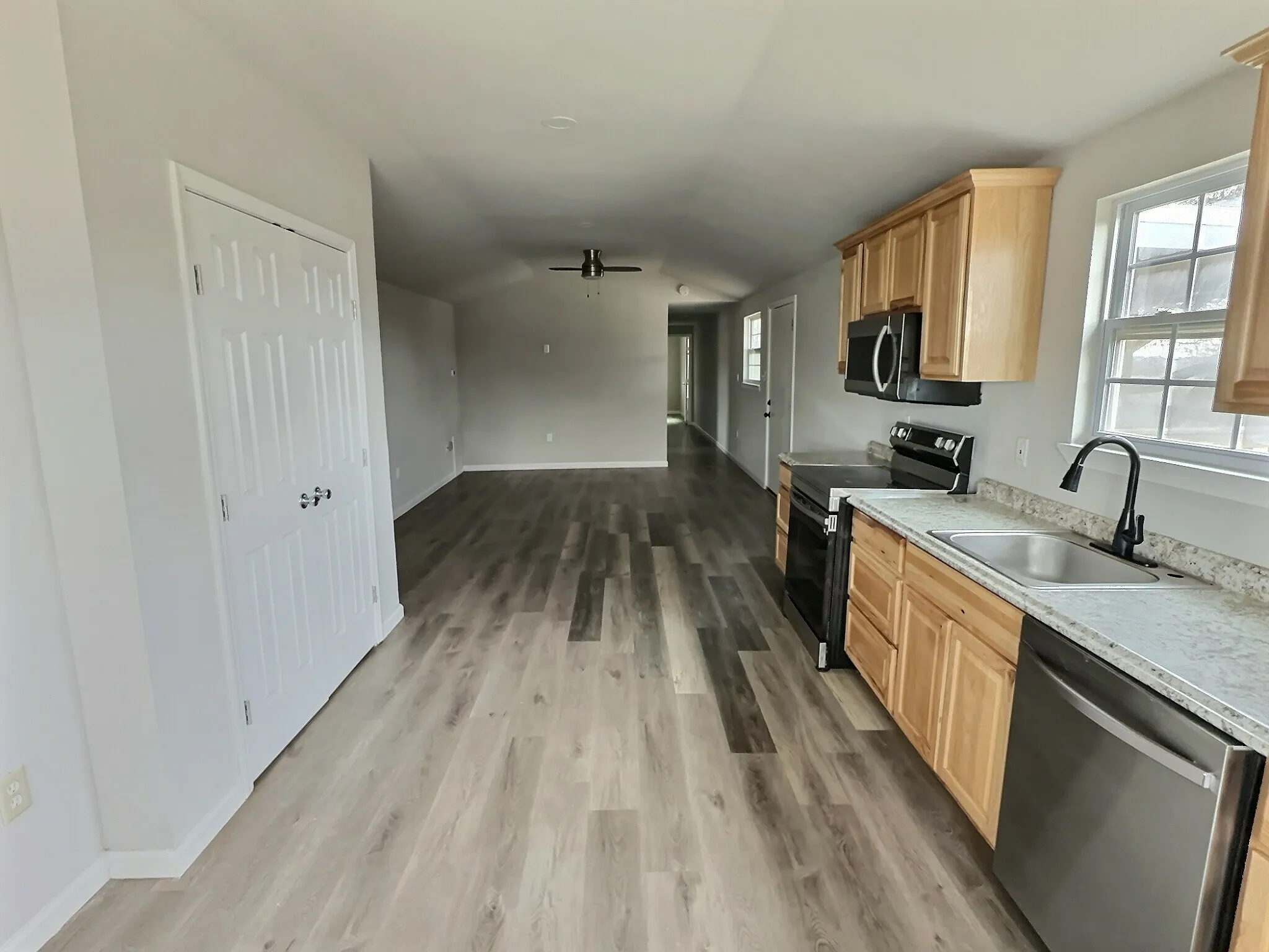 Kitchen with stainless steel appliances, light wood finish cabinets, healthy amount of natural light, ceiling fan, and vaulted ceiling