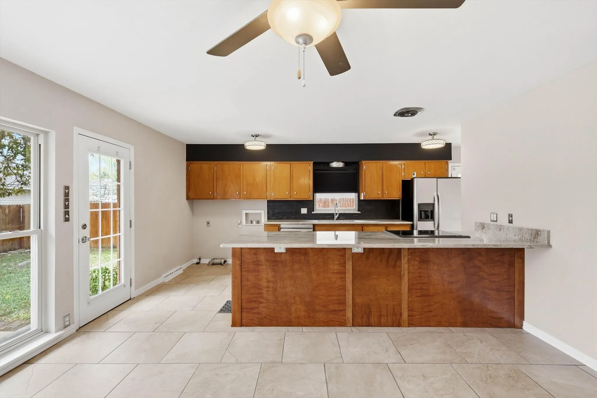 Kitchen with a peninsula, wood finish cabinets, stainless steel fridge, and healthy amount of natural light