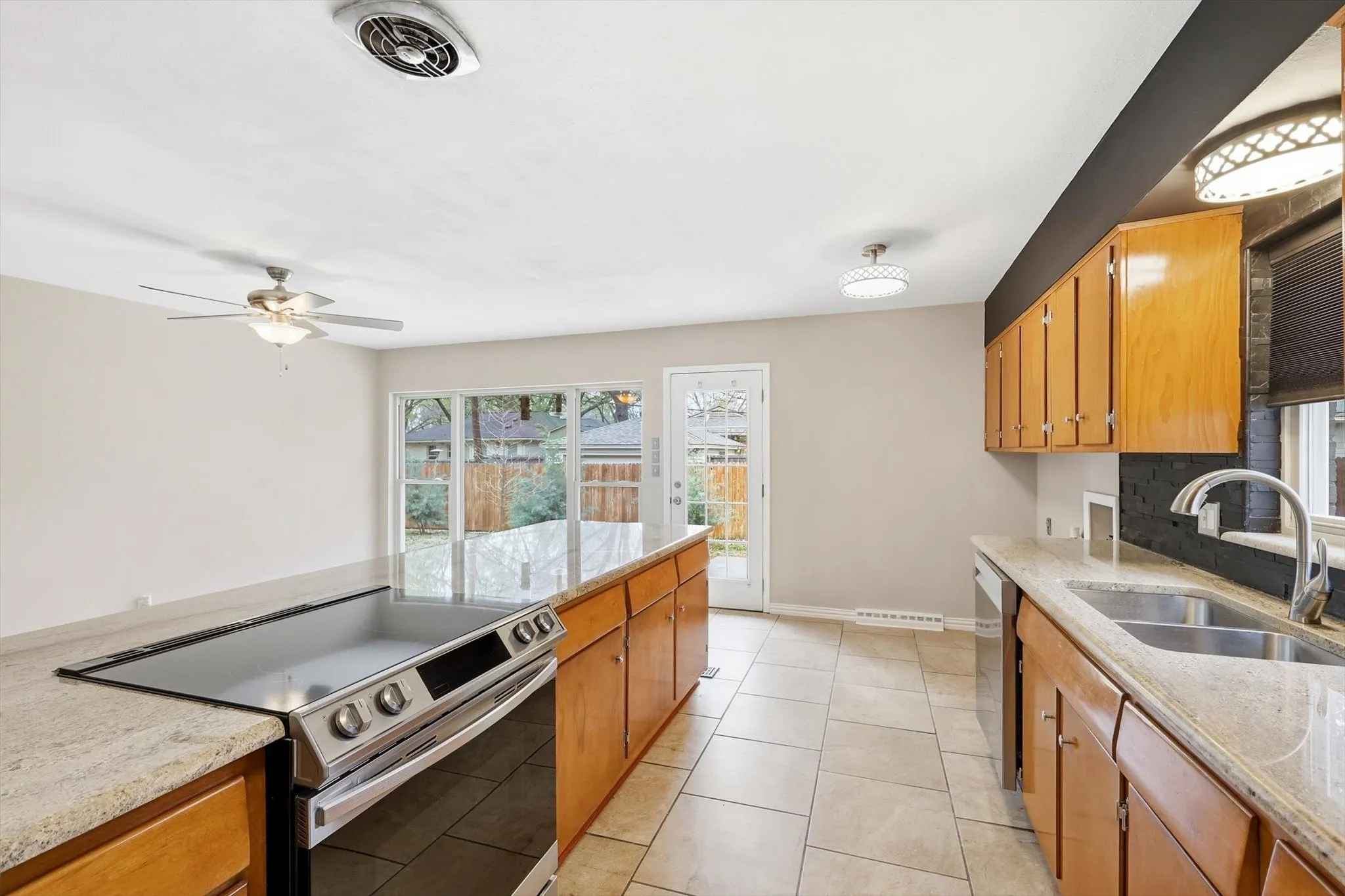 Kitchen featuring stainless steel appliances, light stone counters, and wood finish cabinets
