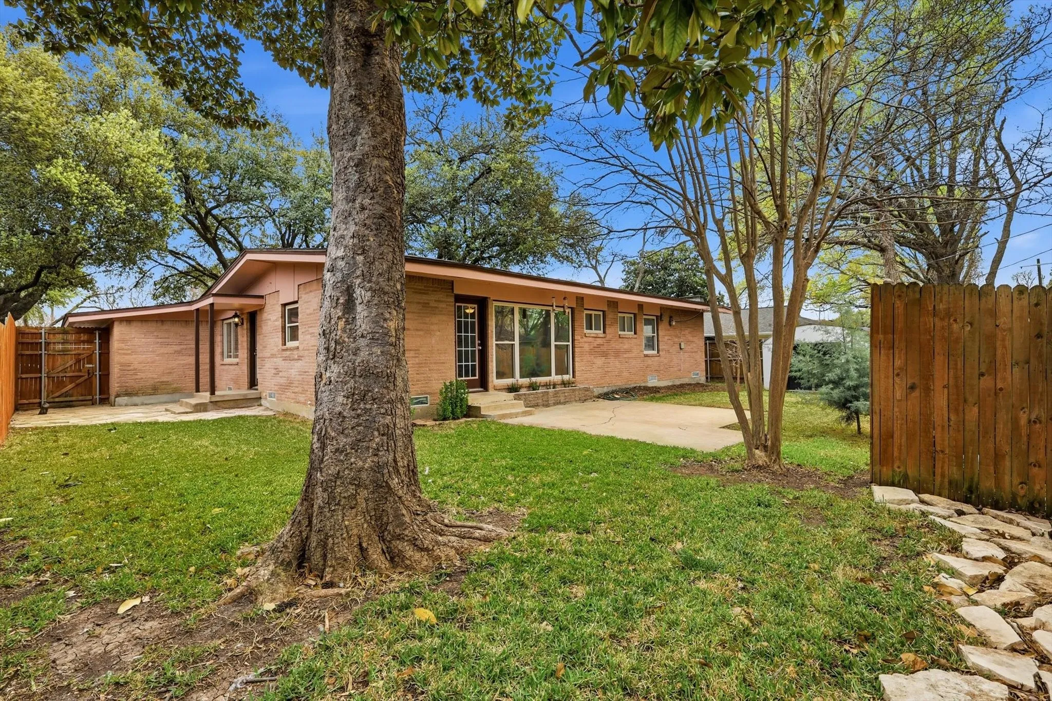 Back of house featuring a patio area, brick siding, entry steps, and a gate