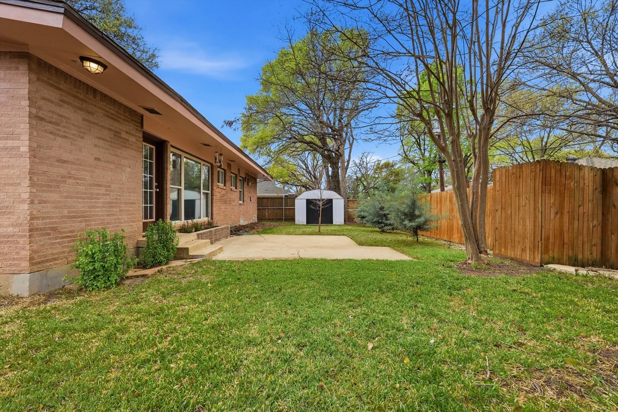 Fenced backyard featuring a patio and a shed