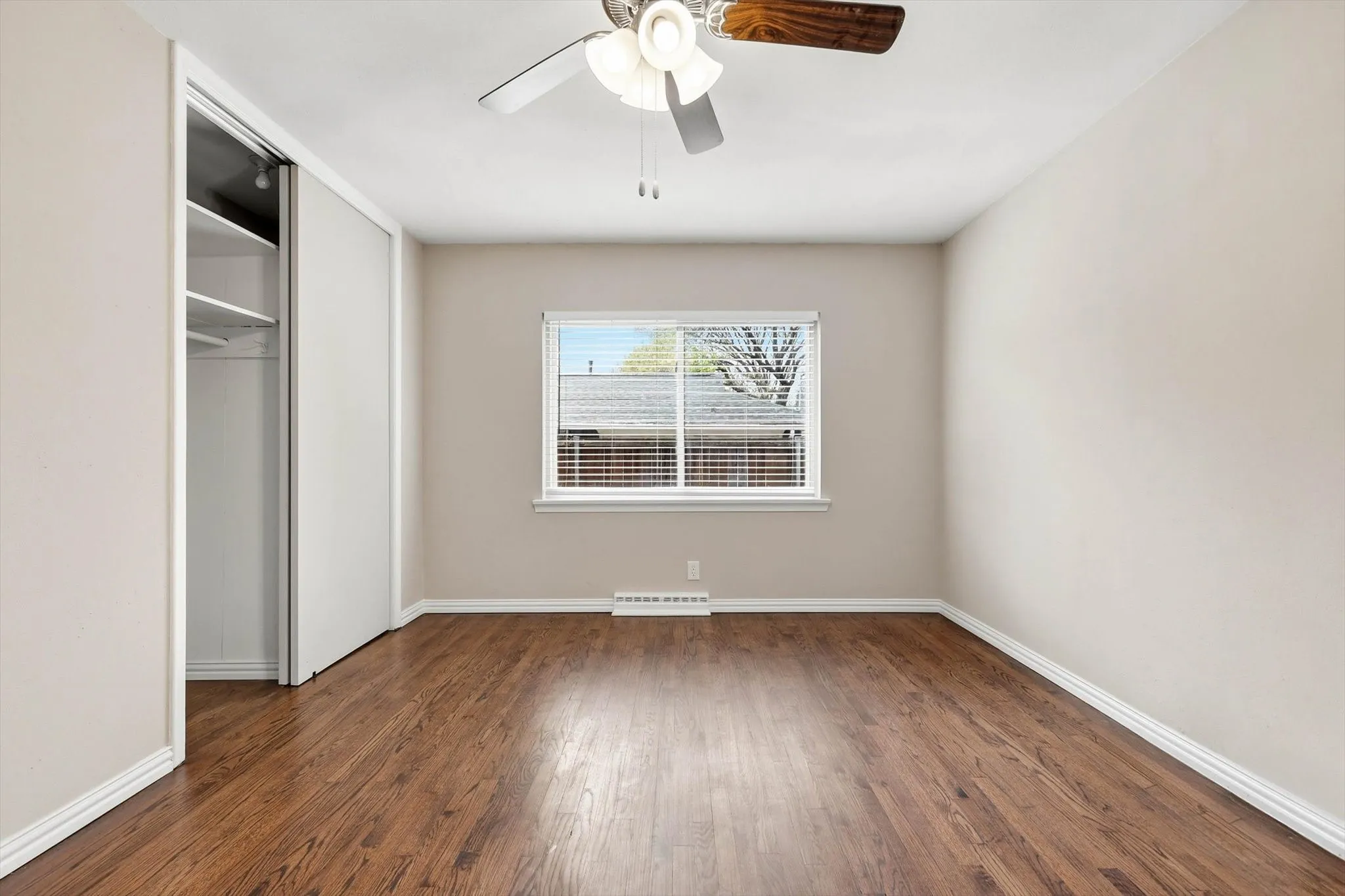 Unfurnished bedroom featuring a closet, dark wood-type flooring, and a ceiling fan