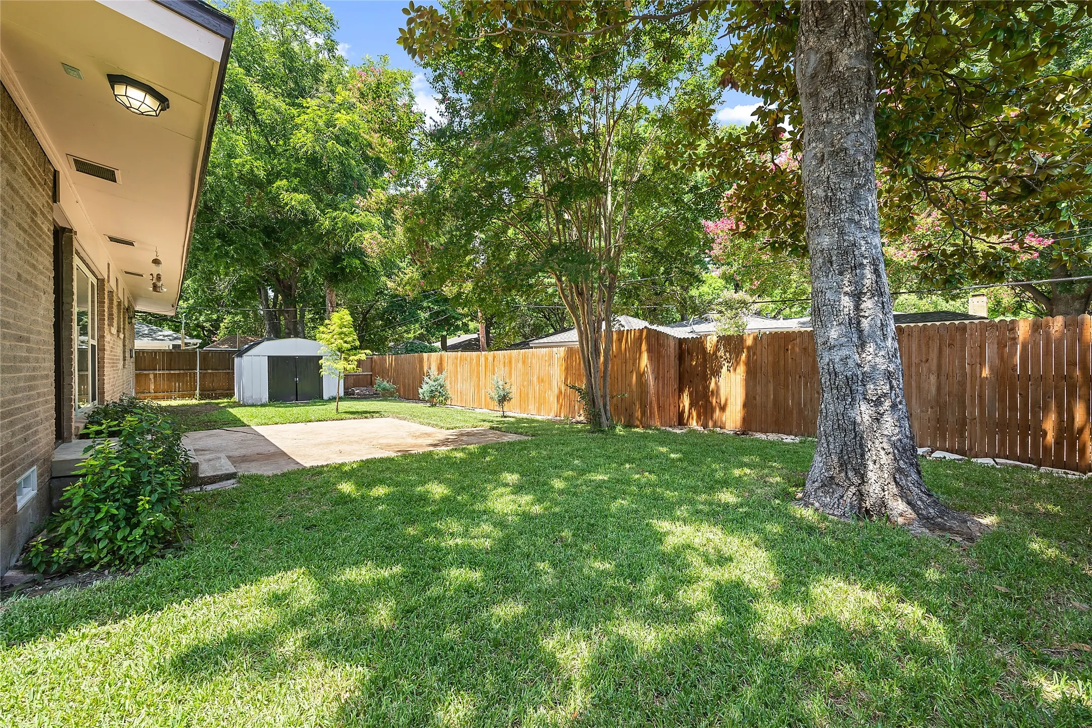 Fenced backyard featuring a patio and a storage shed