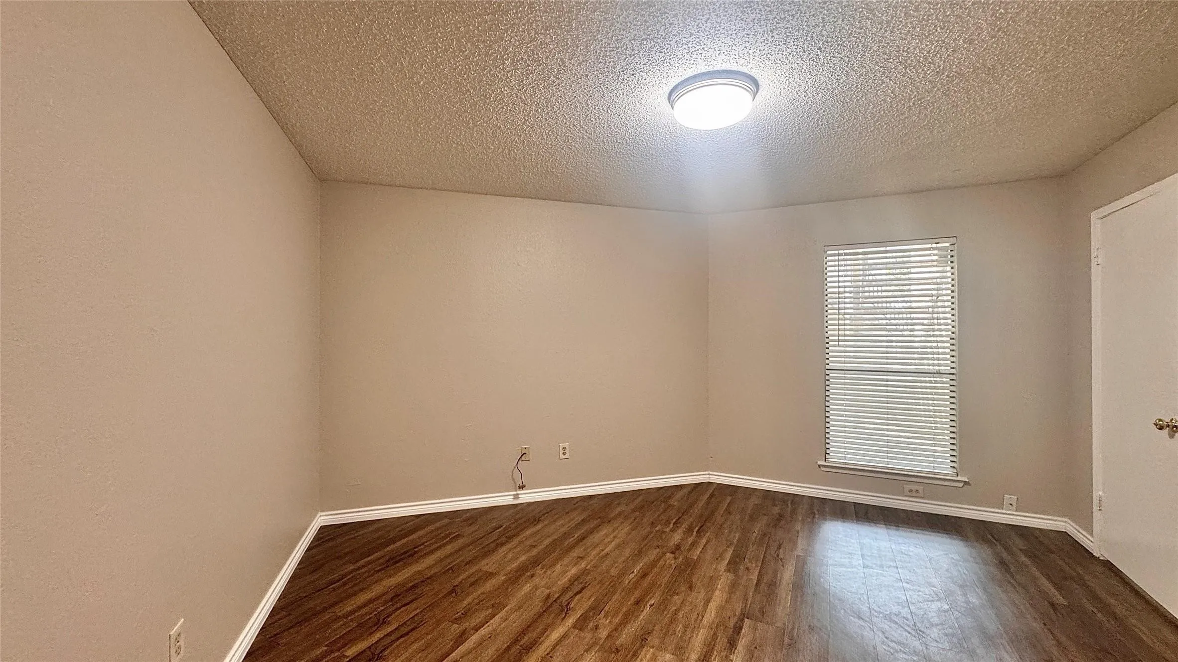 Empty room with a textured ceiling and dark wood finished floors