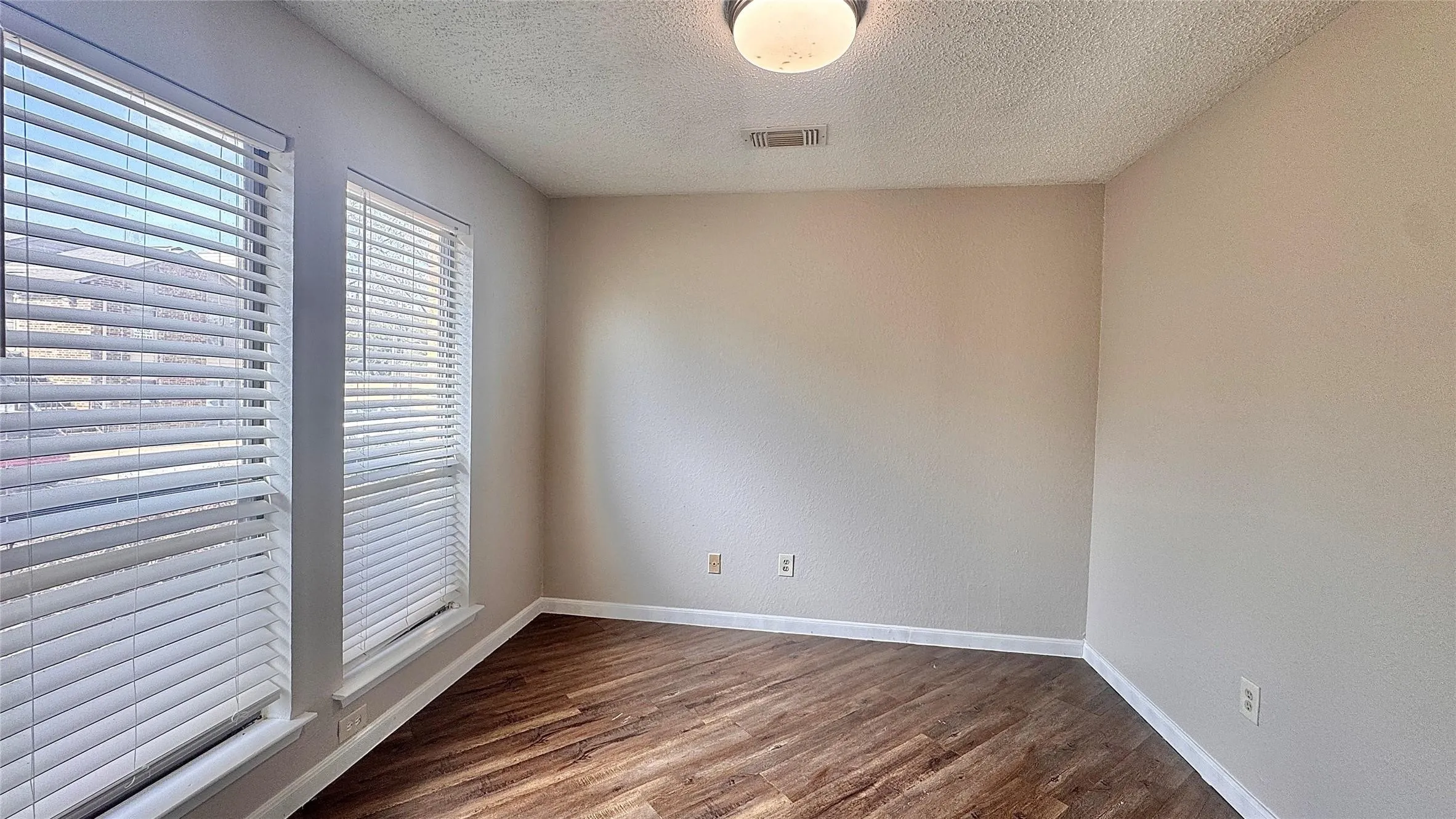 Unfurnished room featuring dark wood finished floors and a textured ceiling