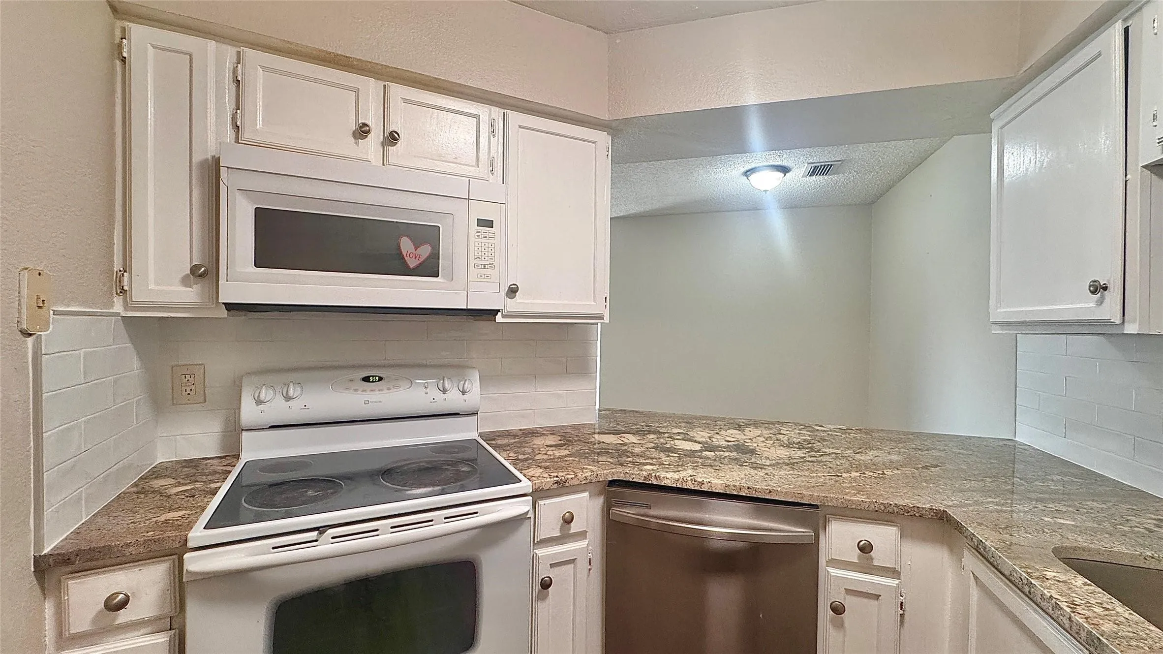 Kitchen with white appliances, white cabinetry, and dark stone countertops
