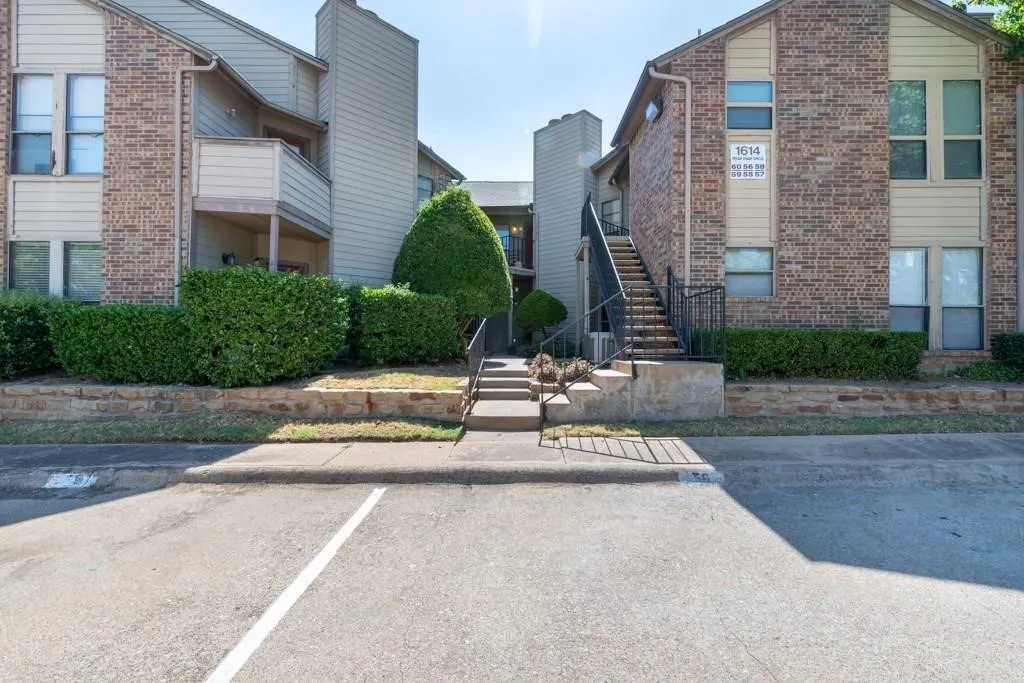 View of building exterior featuring stairway and uncovered parking