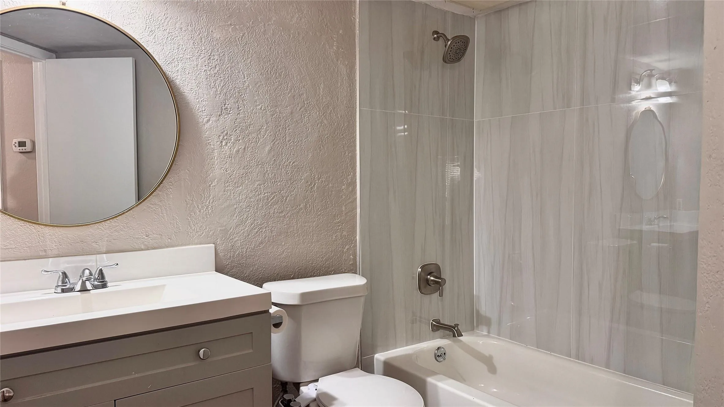 Full bath featuring a textured wall, vanity, and shower / washtub combination