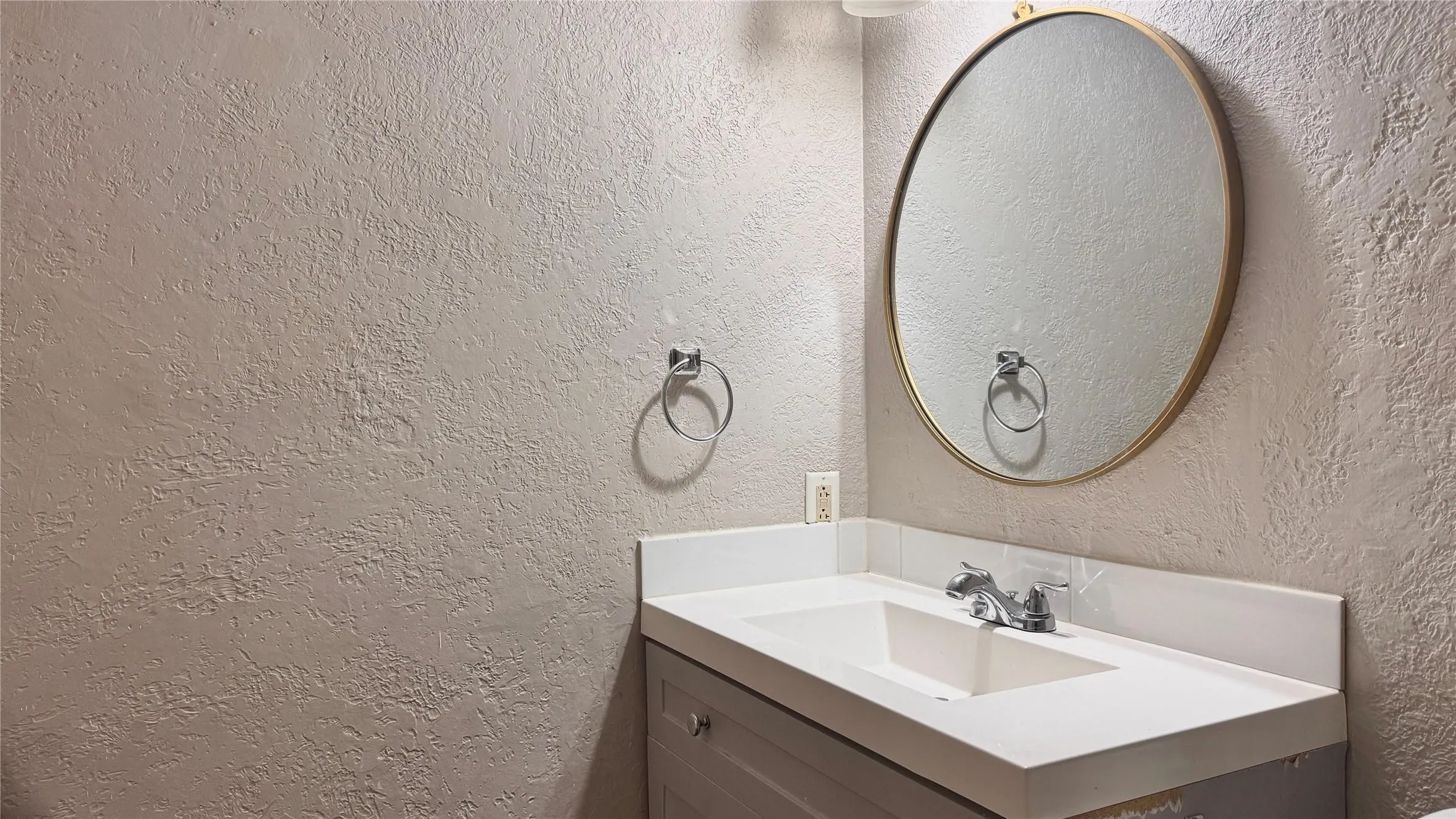 Bathroom featuring vanity and a textured wall
