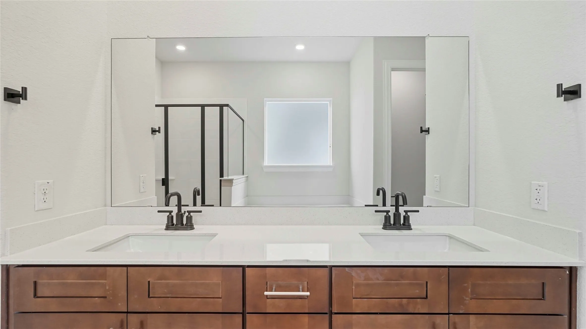 Dual vanity featuring a long integrated mirror, two undermount sinks, and dark wood-finish cabinetry