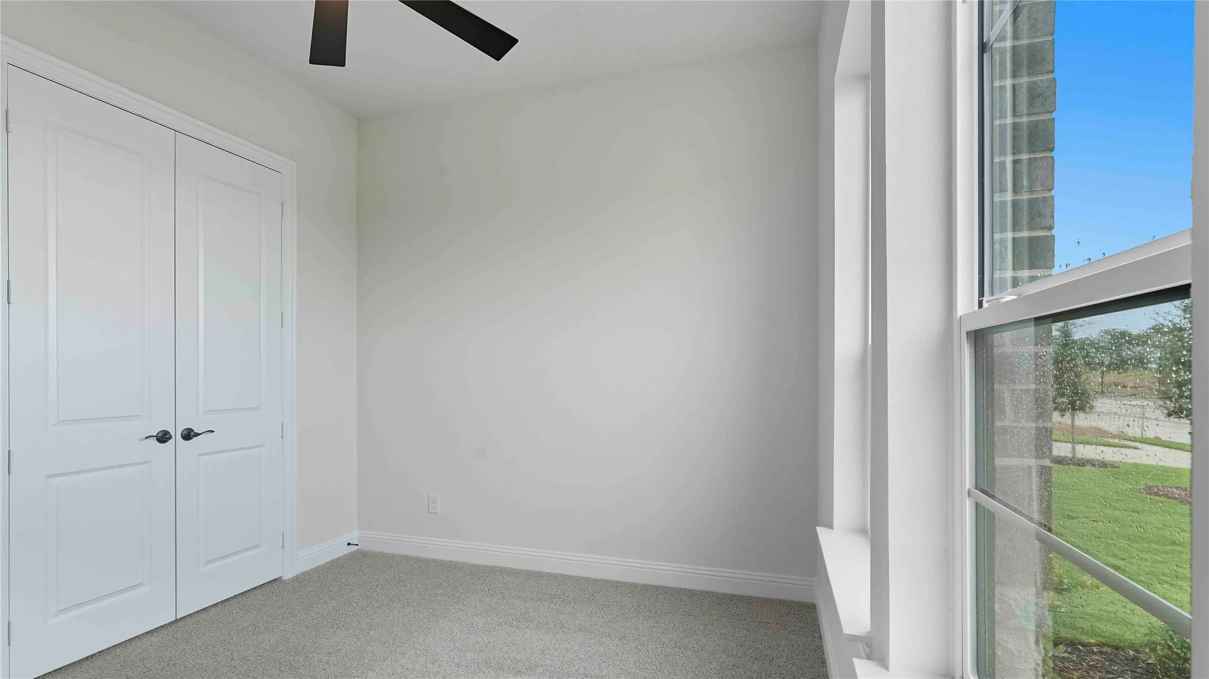 Neutral-toned room featuring a ceiling fan, light gray carpeting, and white baseboards