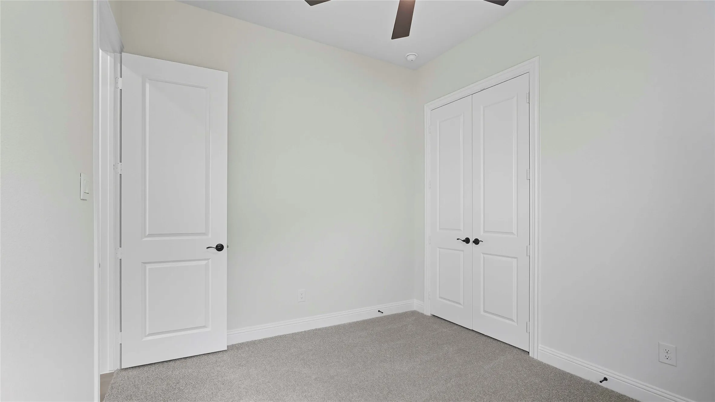 Neutral-toned room with light gray carpeting and white baseboards