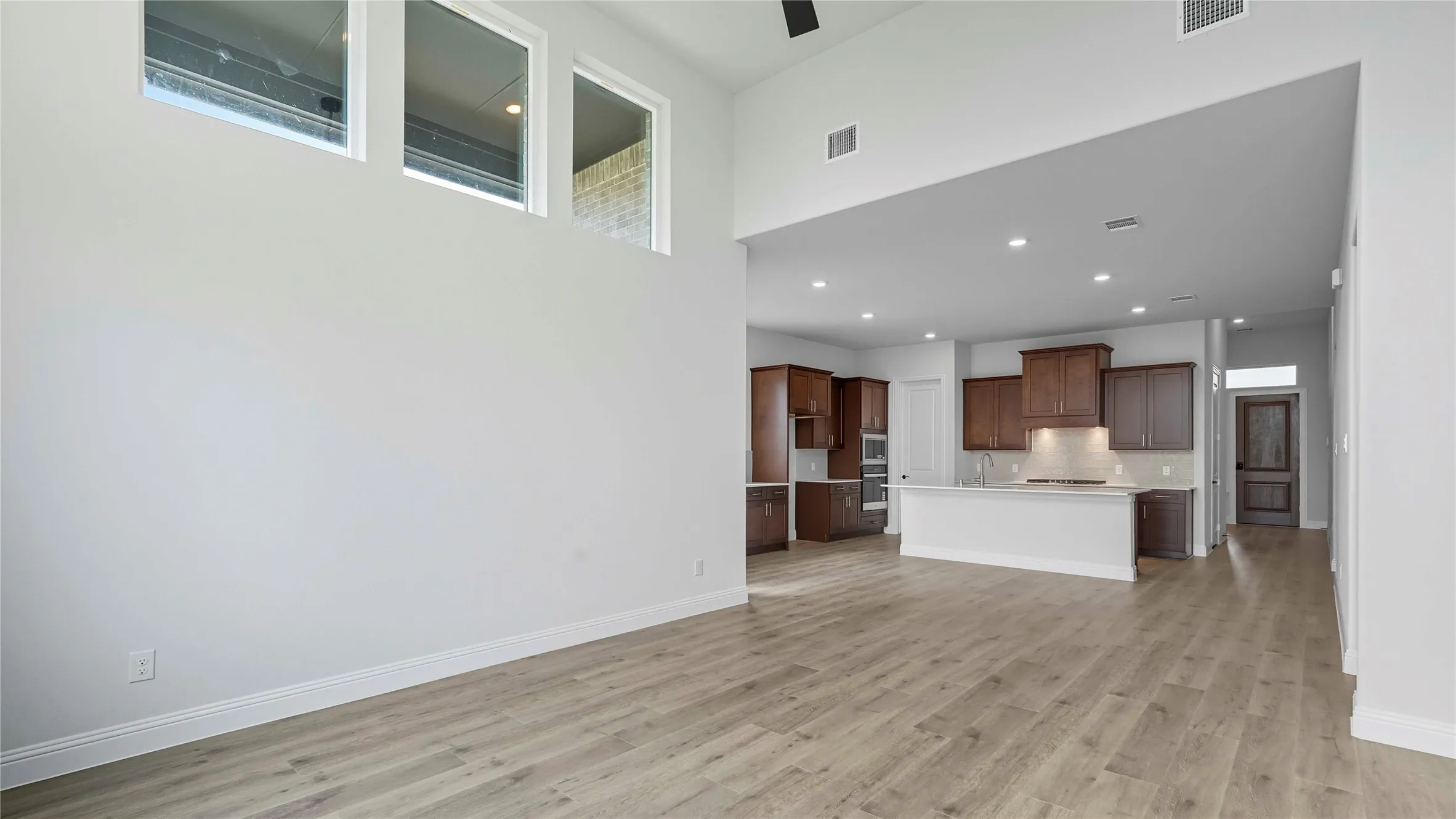 Expansive living area with wood-finish flooring, high ceilings, and a large wall for customization