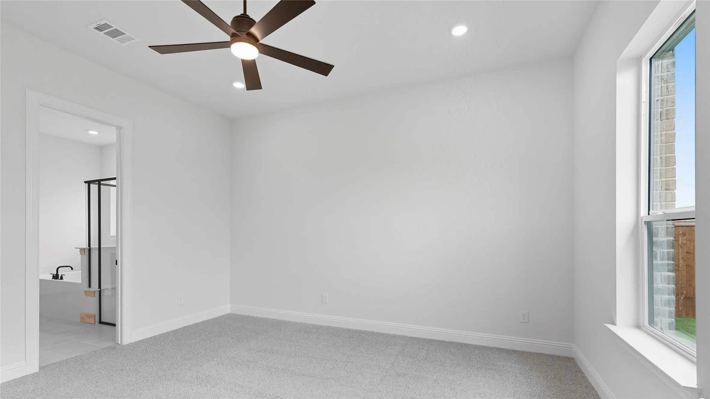 Spacious room with plush gray carpeting and a ceiling fan with integrated lighting