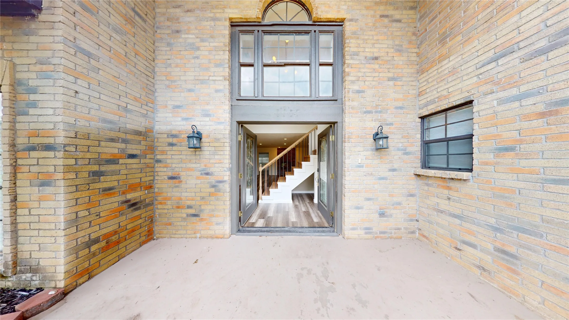 View of exterior entry with brick siding and a patio area