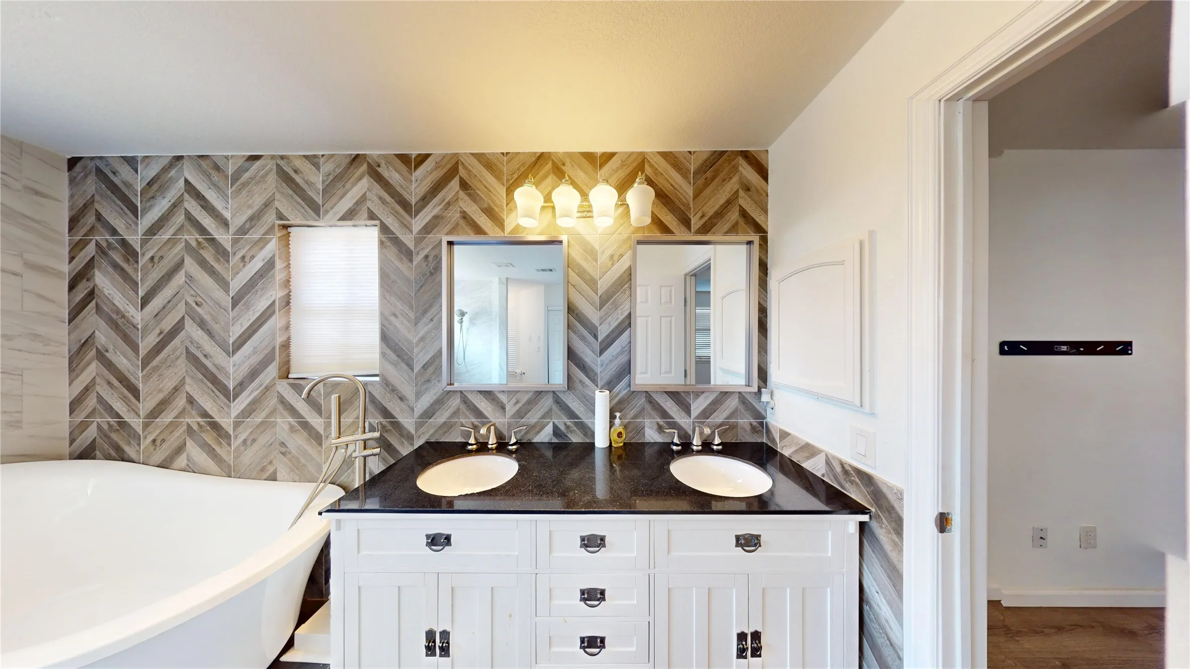 Bathroom with double vanity, a soaking tub, and tile walls