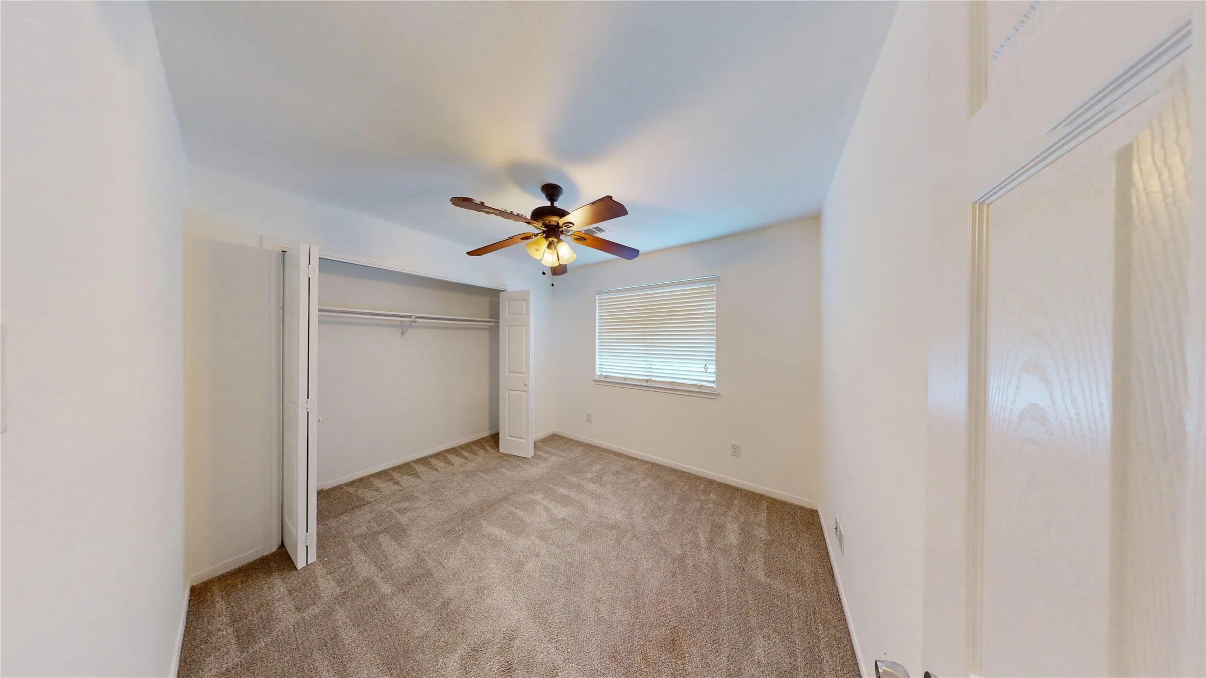 Unfurnished bedroom with ceiling fan, a closet, and light carpet