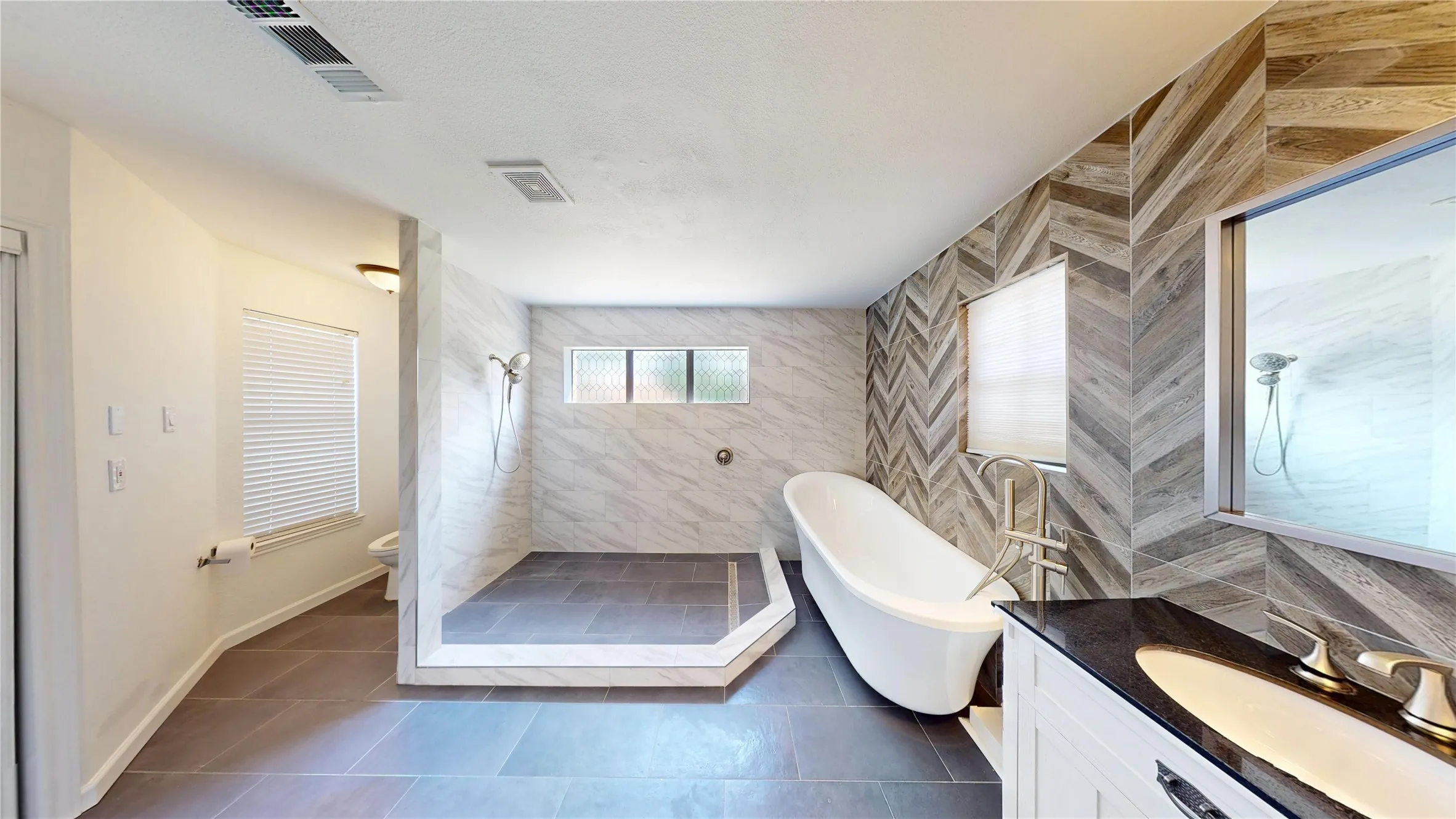 Full bathroom with vanity, a walk in shower, tile walls, dark tile patterned flooring, and a freestanding tub