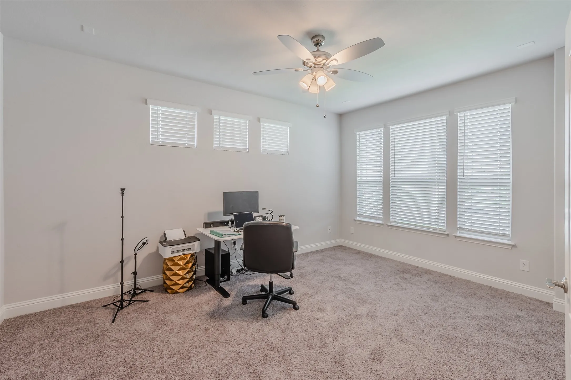 Office space with light carpet and ceiling fan