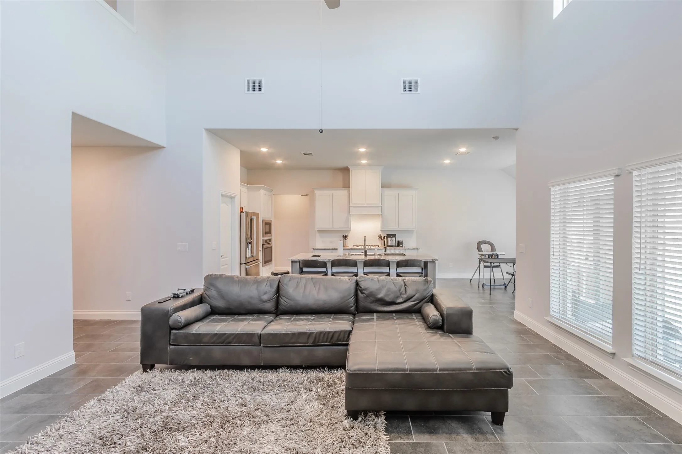 Living room featuring ceiling fan, a high ceiling, and recessed lighting