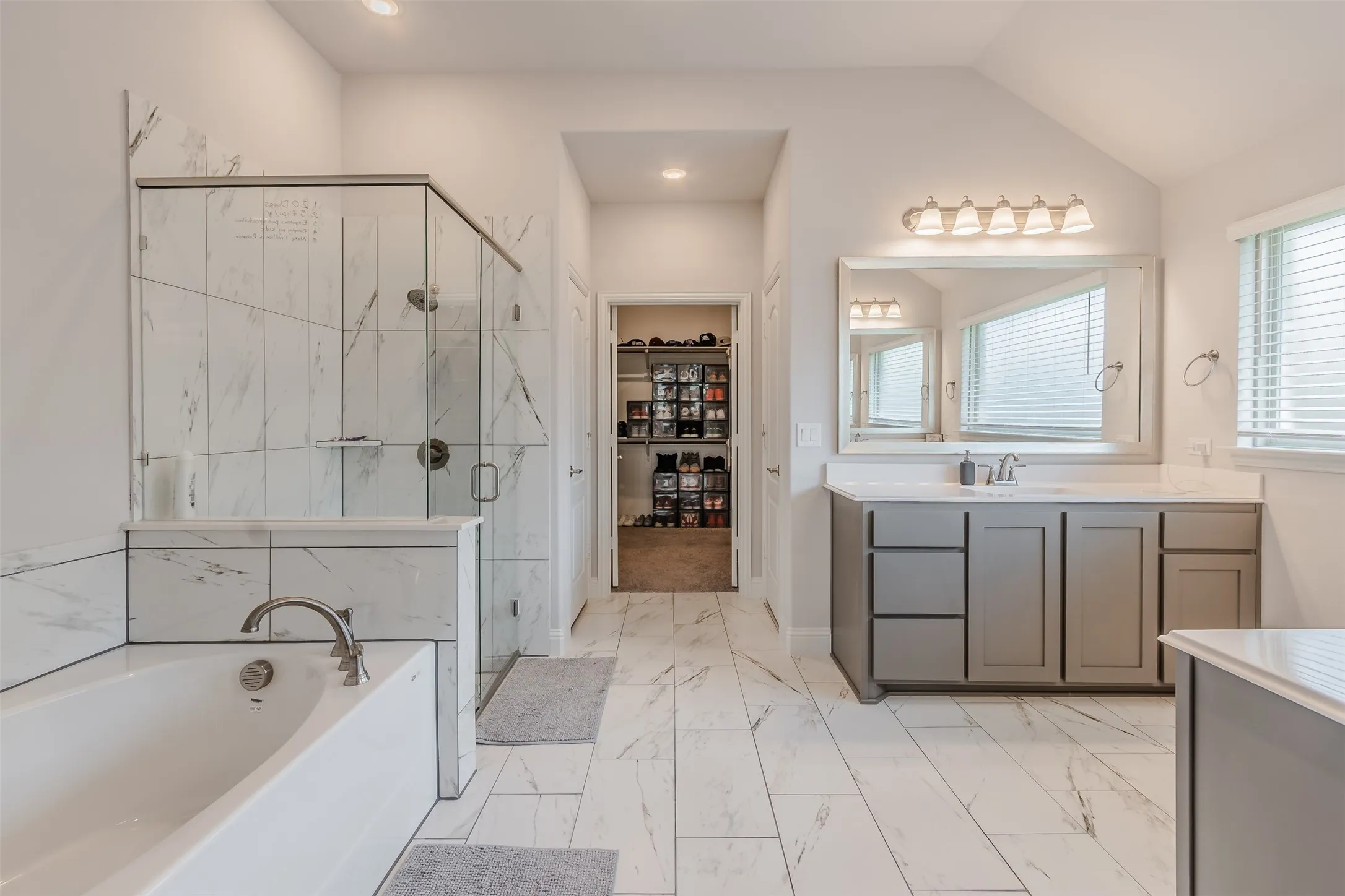 Bathroom with vanity, a marble finish shower, a garden tub, a walk in closet, and light marble finish flooring