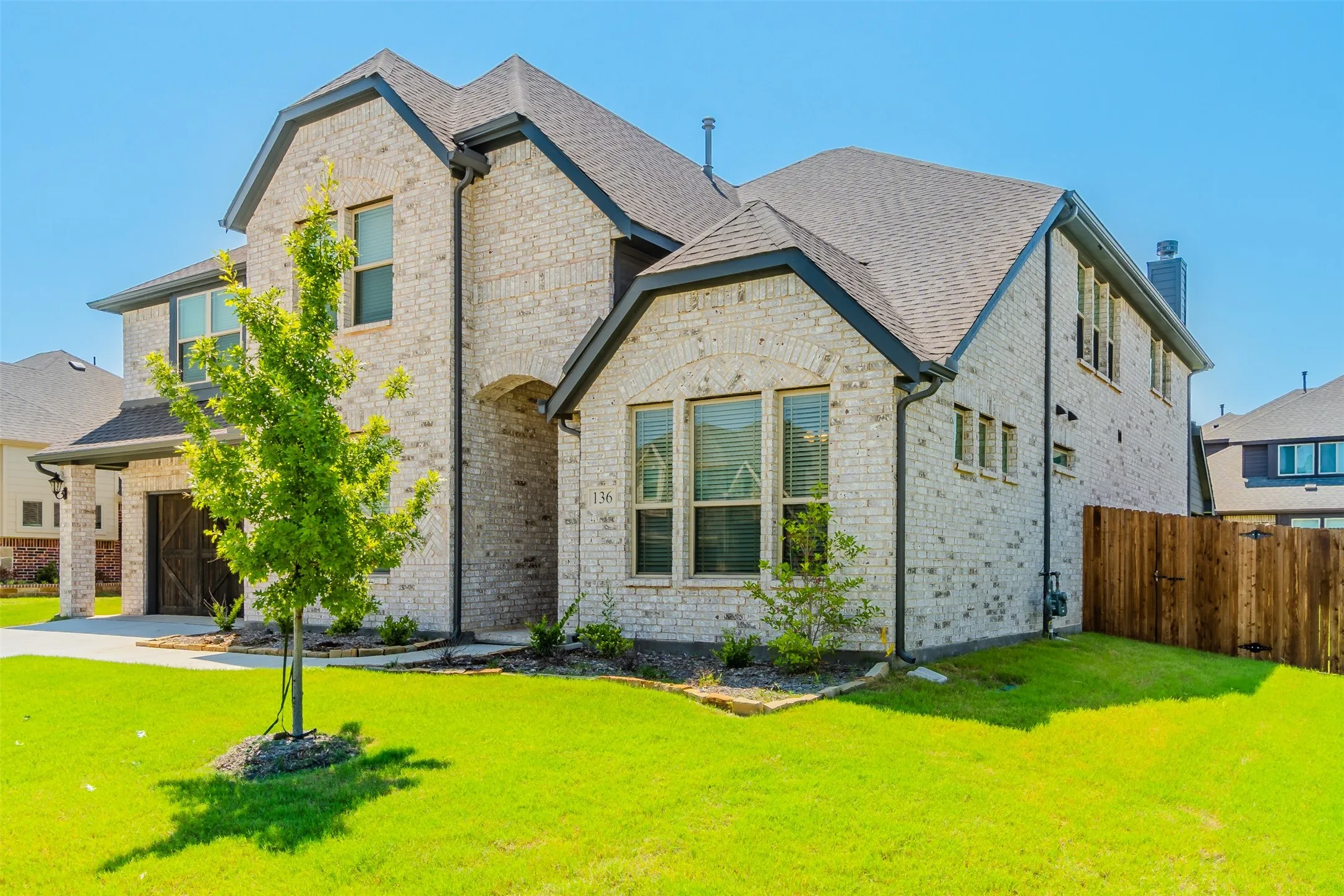 View of front of property with brick siding, a chimney, a garage, concrete driveway, and a shingled roof