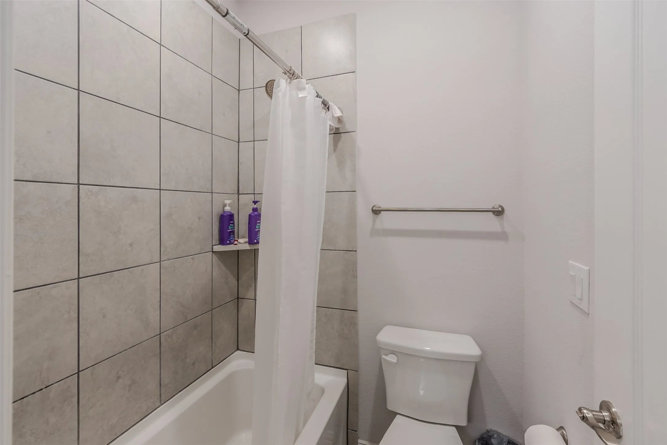 Bathroom with toilet and shower / bath combo with shower curtain