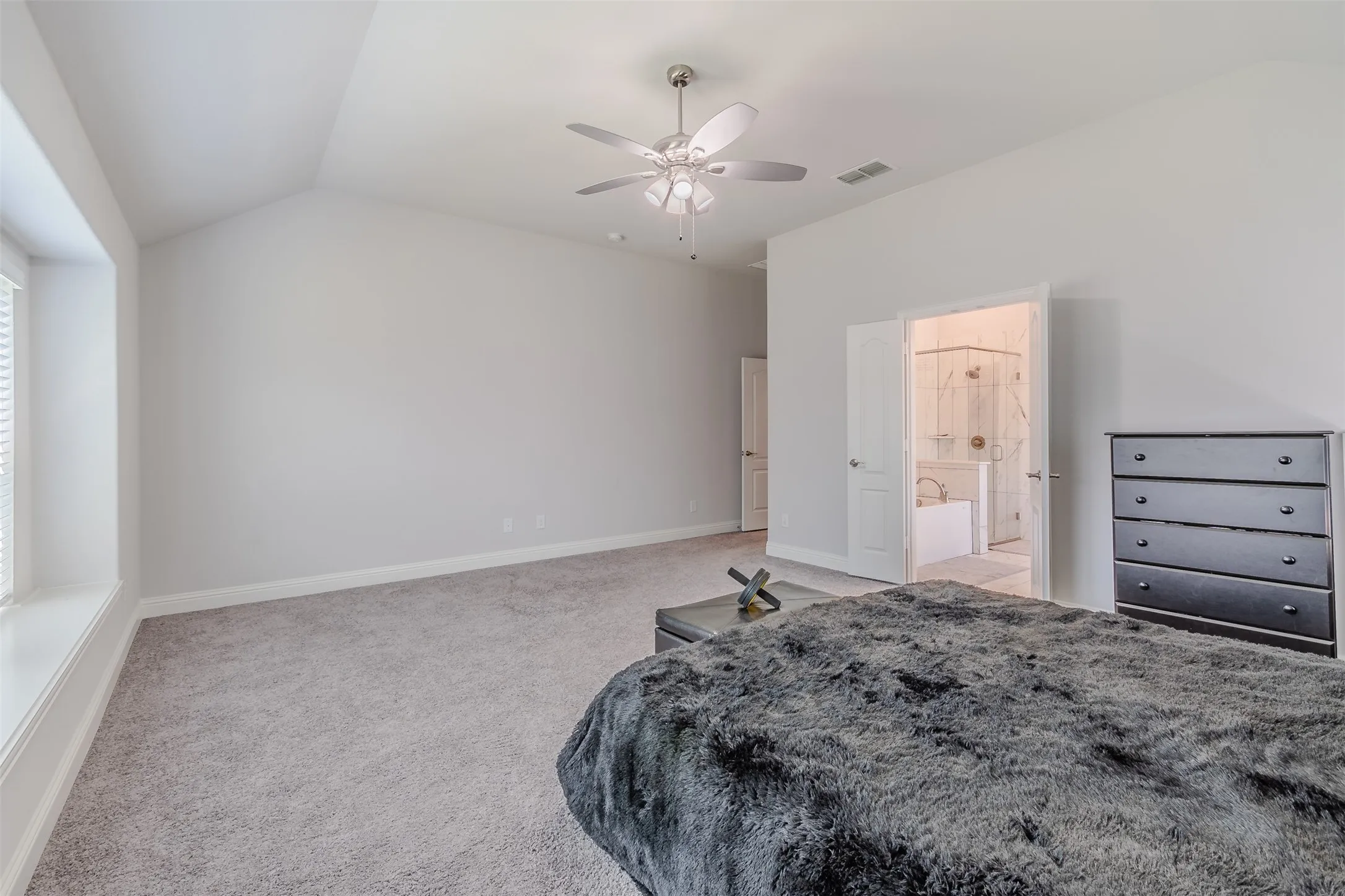 Bedroom featuring lofted ceiling, light colored carpet, a ceiling fan, and ensuite bath