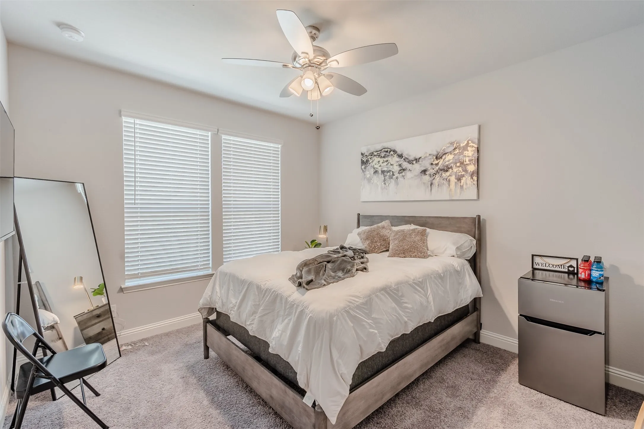 Bedroom with stainless steel refrigerator, a ceiling fan, and light colored carpet