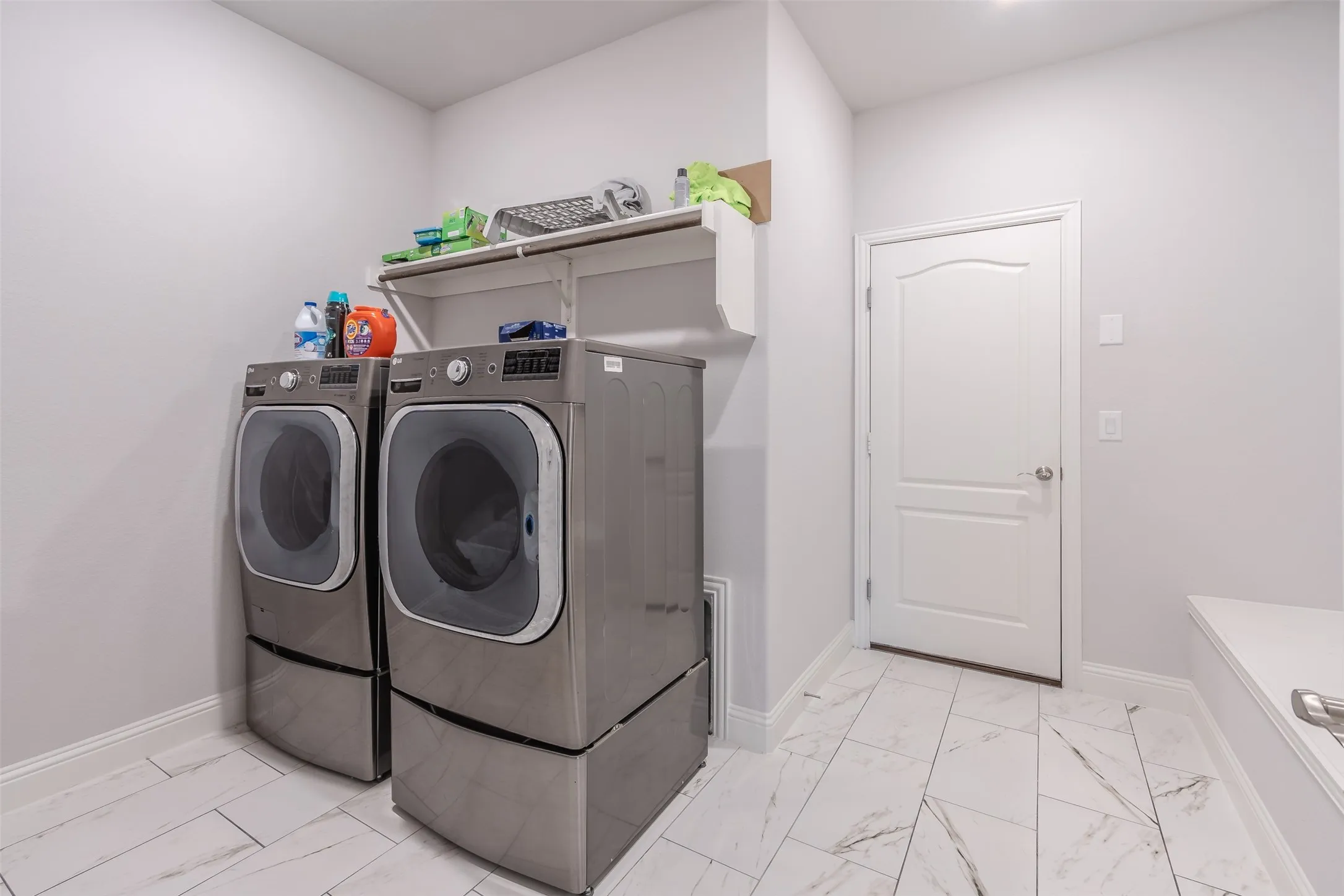 Laundry area featuring light marble finish floors and washing machine and dryer