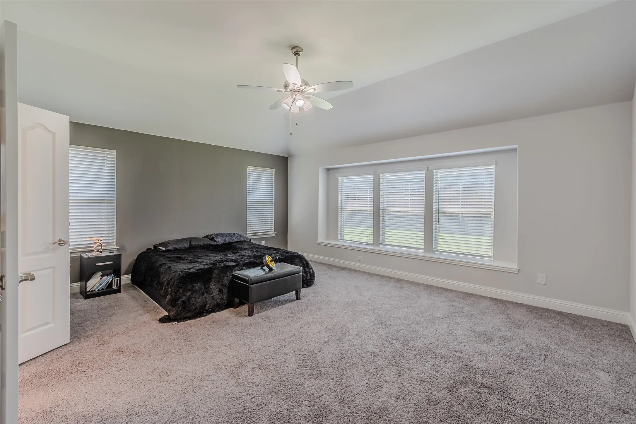 Carpeted bedroom with ceiling fan and lofted ceiling