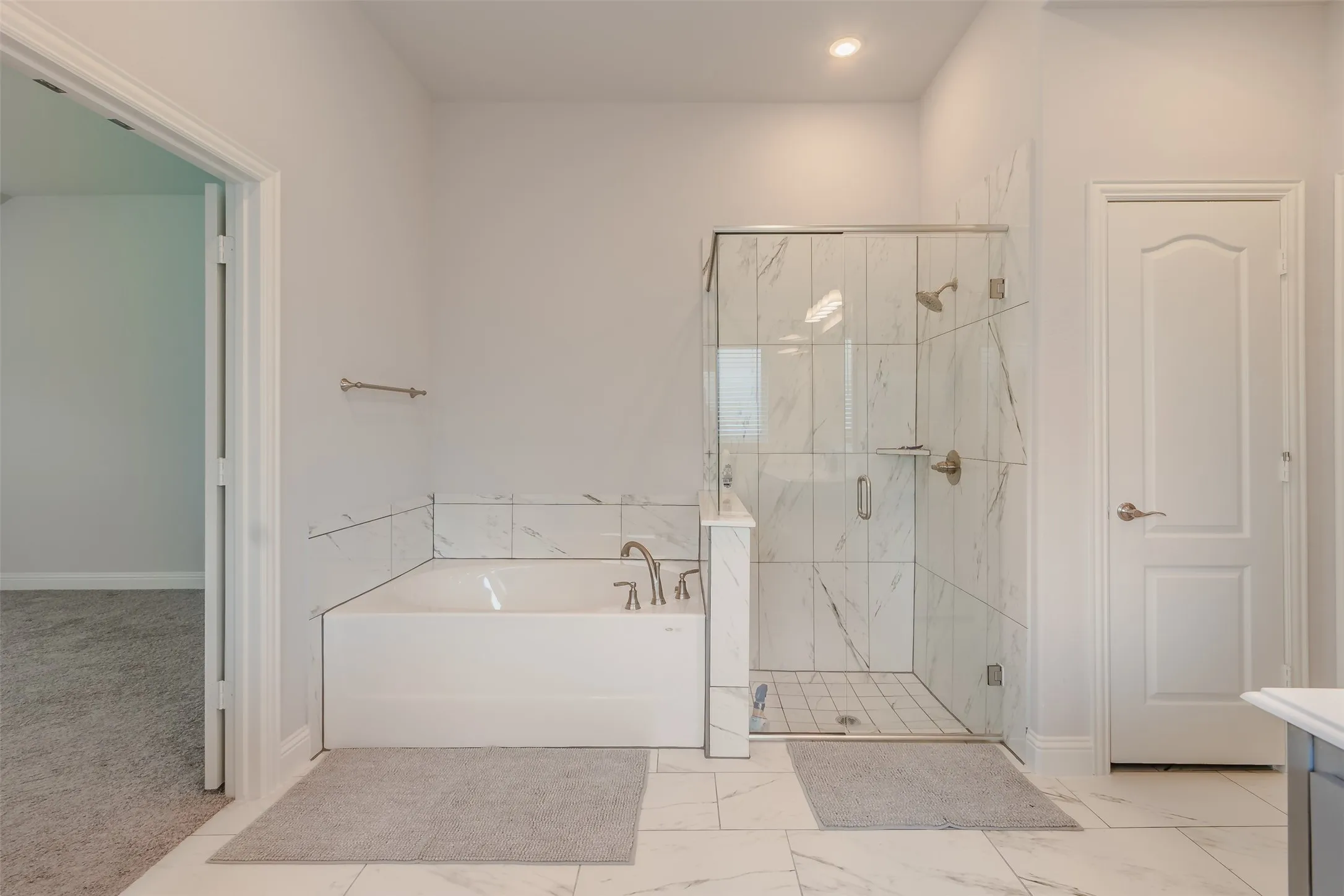 Bathroom featuring a marble finish shower, a bath, vanity, and light colored carpet